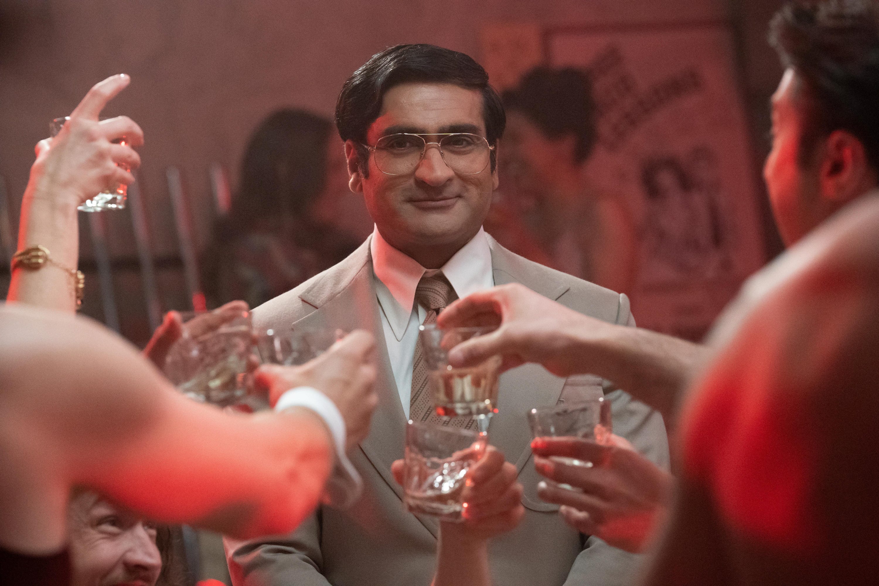 Steve (Kumail Nanjiani) trägt einen Anzug mit einer Gruppe von Leuten, die in einem Nachtclub aus der Serie „Welcome to Chippendales“ auf ihn anstoßen.