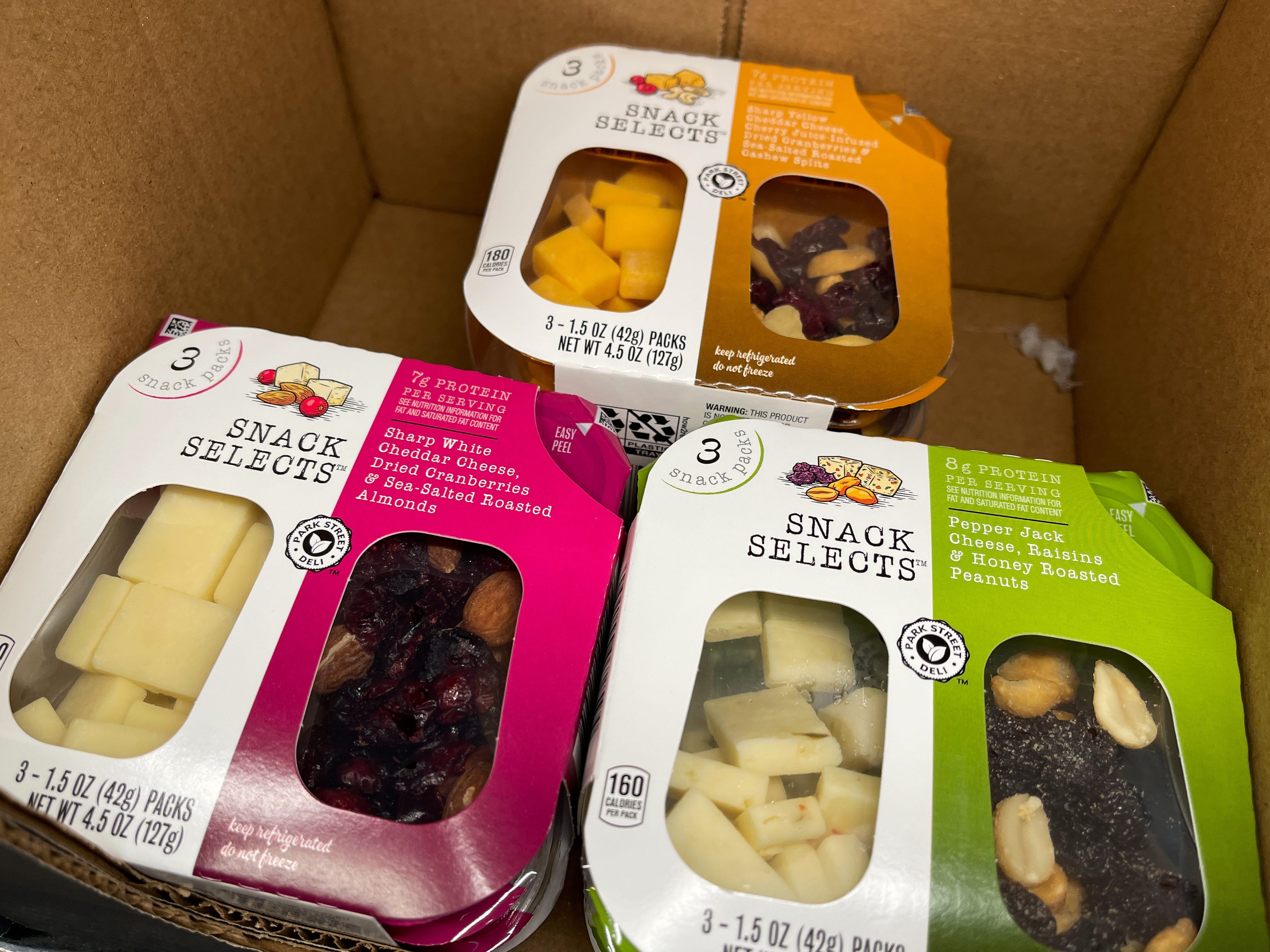 Baumbehälter mit Käse, Obst und Nüssen in einem Karton