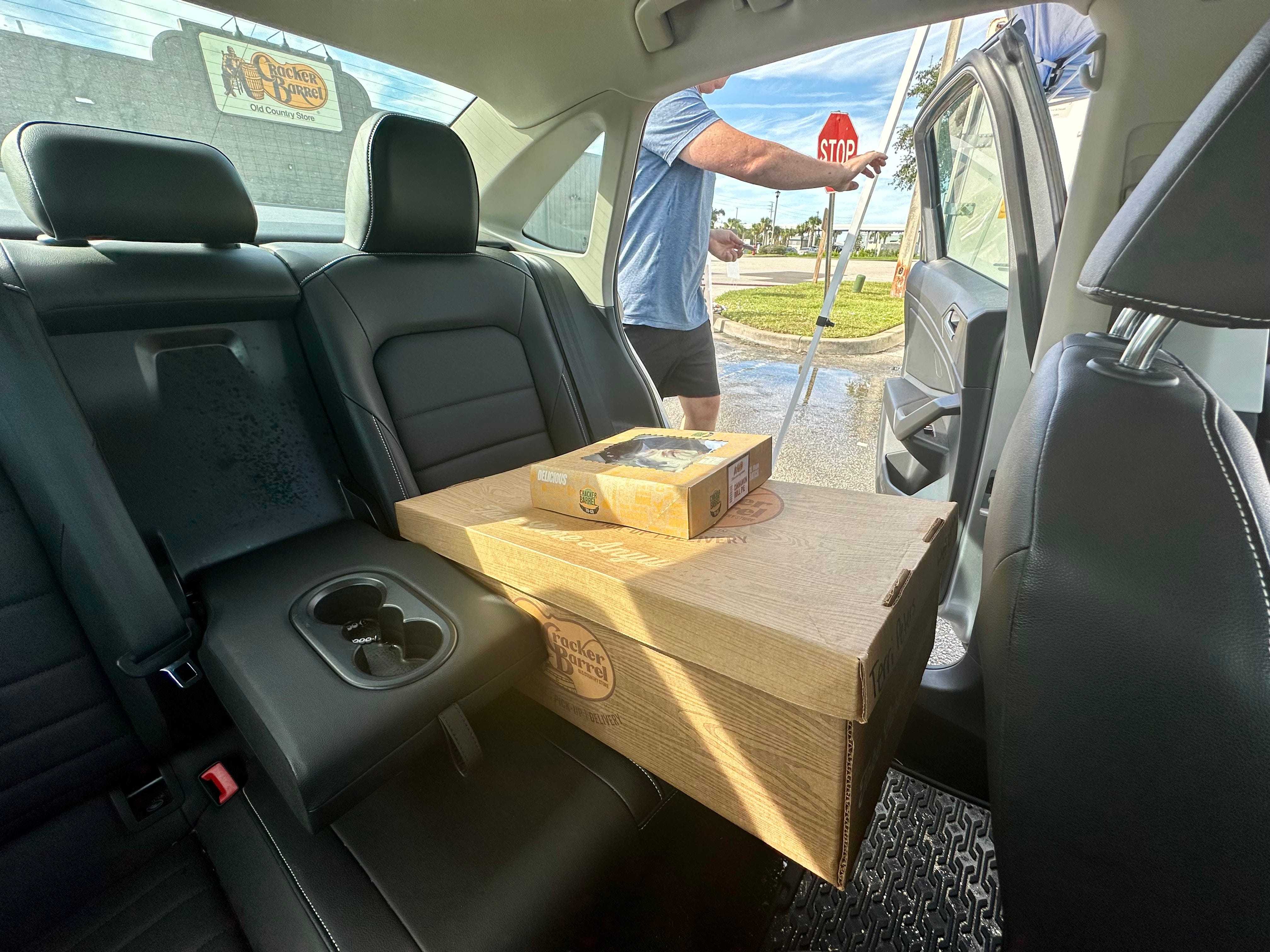 Große Cracker-Fass-Box mit kleinerer Box oben auf dem Rücksitz eines Autos, während ein Mann die Autotür schließt