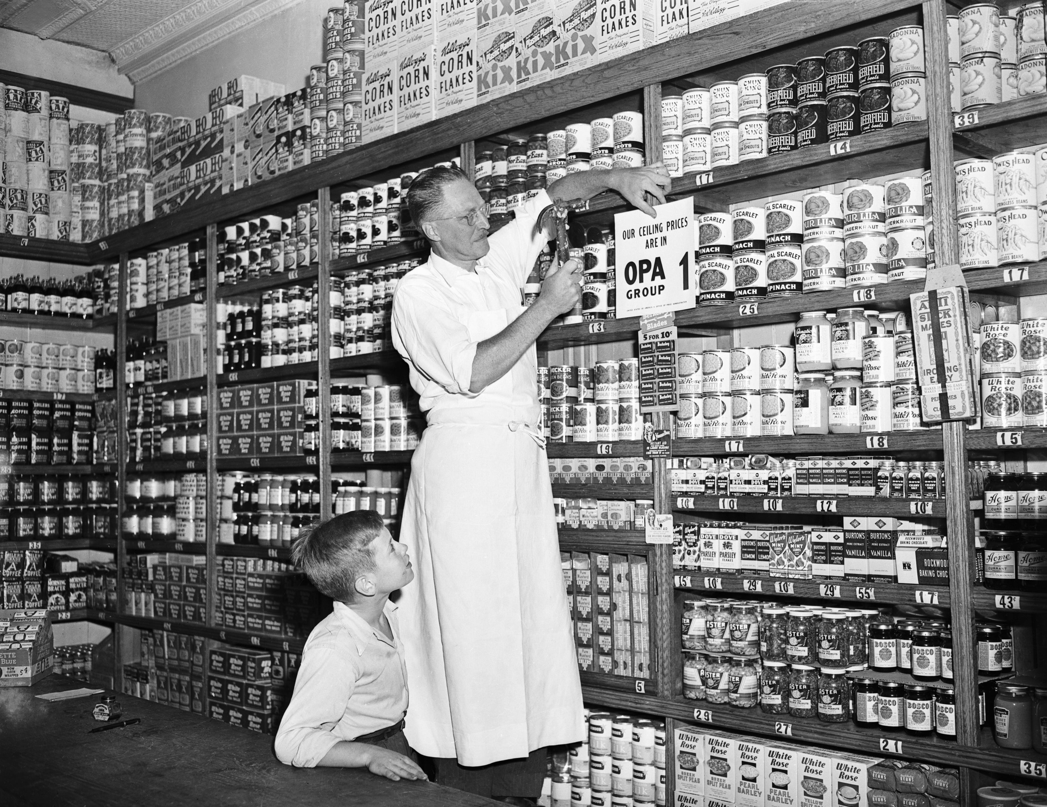 Ladenbesitzer meldet sich im Lebensmittelgeschäft an (Originalunterschrift) 01.08.1946 – New York, NY: Charles Zobel in der Lebensmittelabteilung von Al's Food Market, 468 Dean St., Brooklyn, heftet ein neues OPA-Schild an