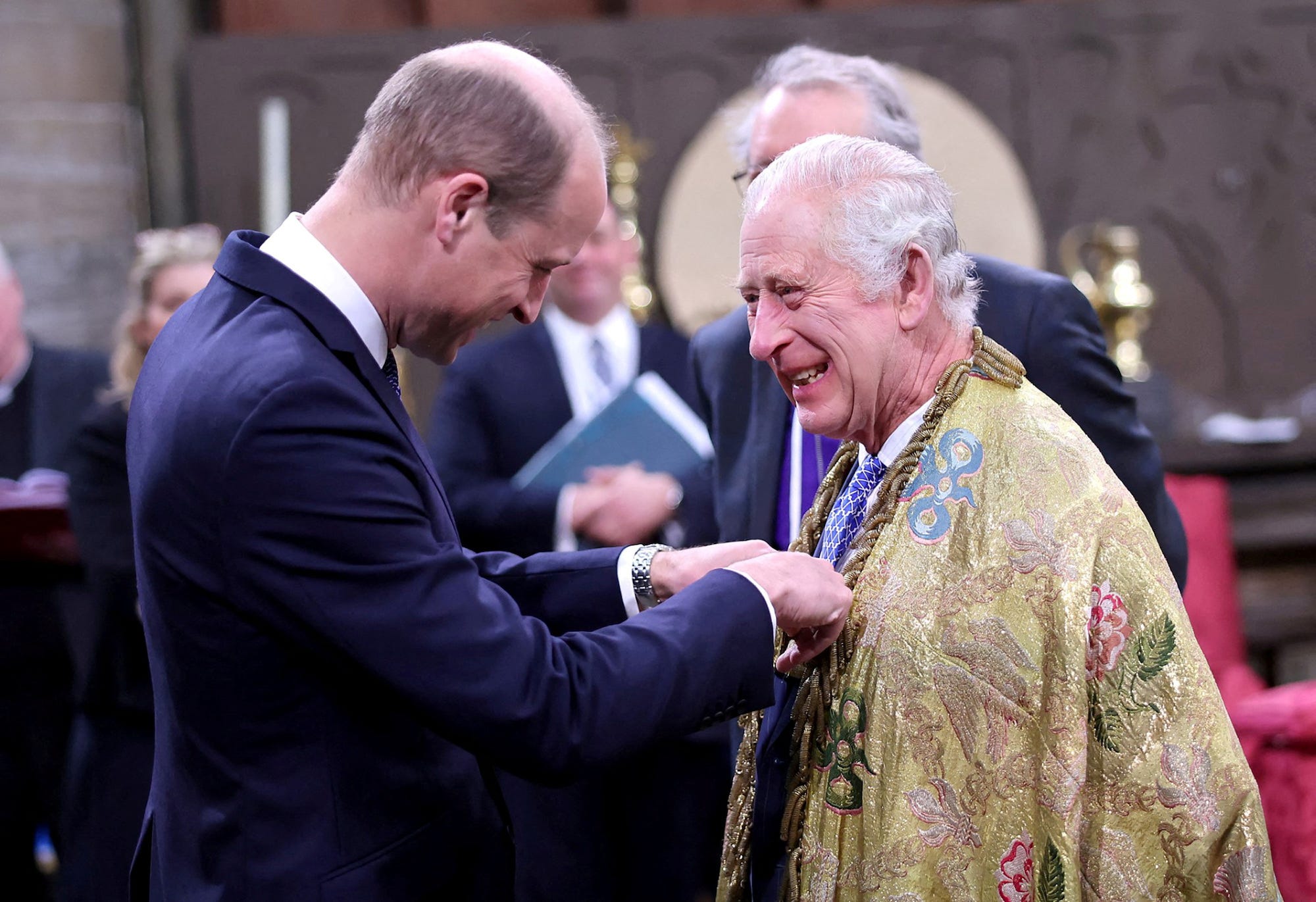 König Charles lacht, als Prinz William ihm etwas an die Brust heftet.