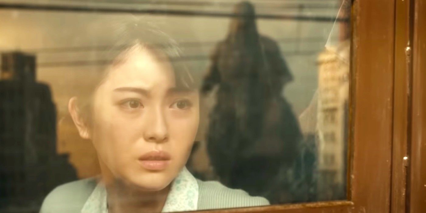 Eine Frau blickt in Godzilla Minus One aus dem Fenster auf Godzilla