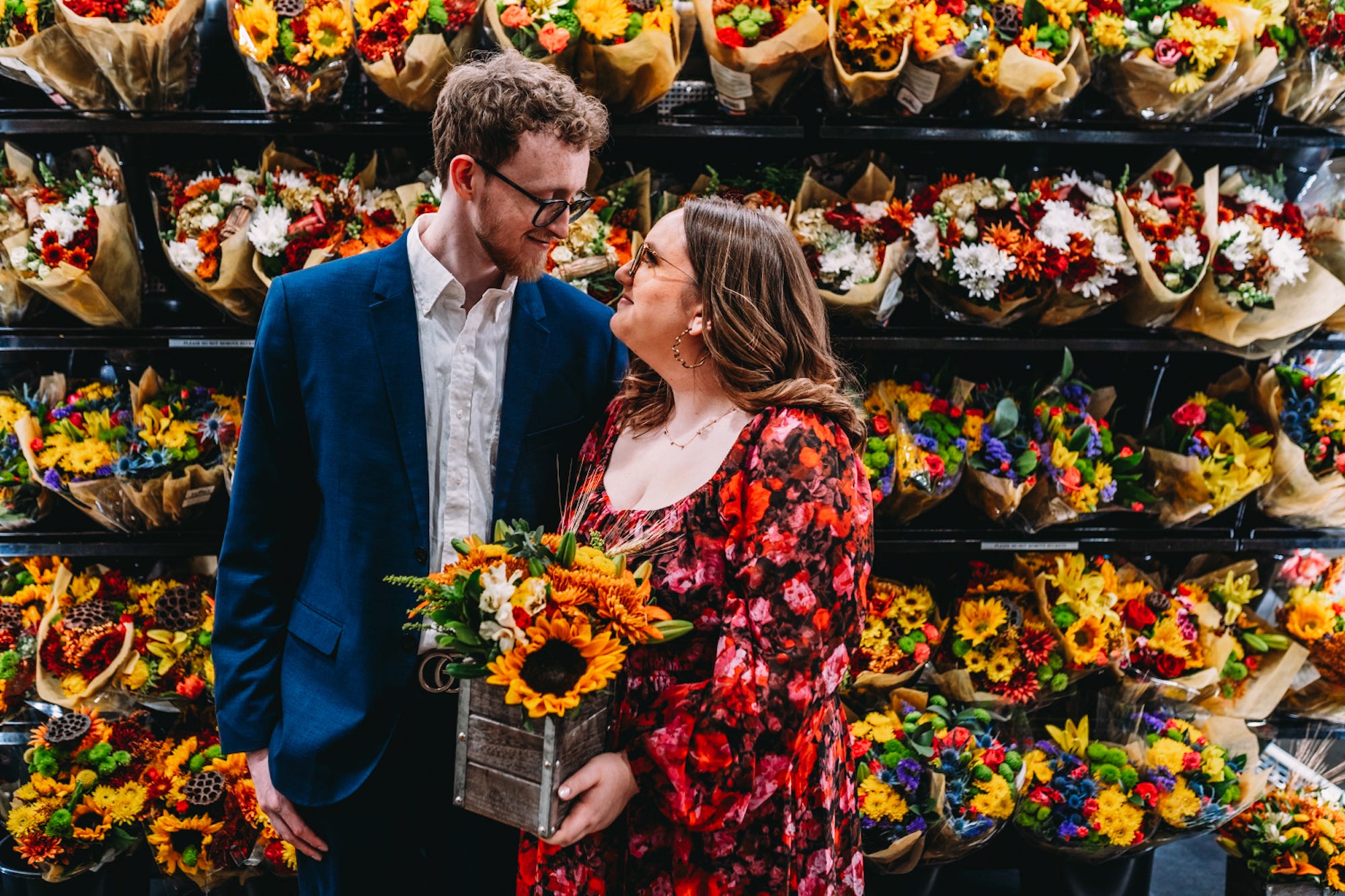 Ein Paar schaut sich vor einer Blumenpräsentation an und hält einen Blumenstrauß in der Hand.