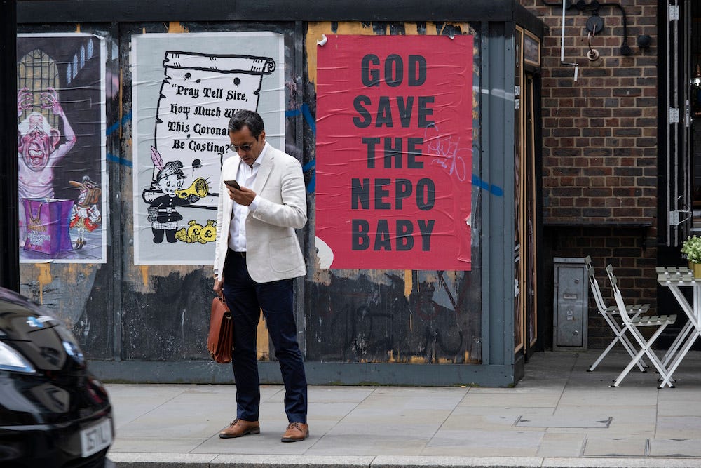 Auf einem roten Plakat mit schwarzem Text, das im Mai 2023 im Osten Londons an eine Wand geklebt ist, steht „God save the nepo baby“.