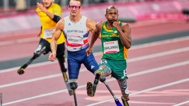 Ntando Mahlangu sprintet im T61-200-m-Finale der Paralympics in Tokio, mit Richard Whitehead hinter ihm
