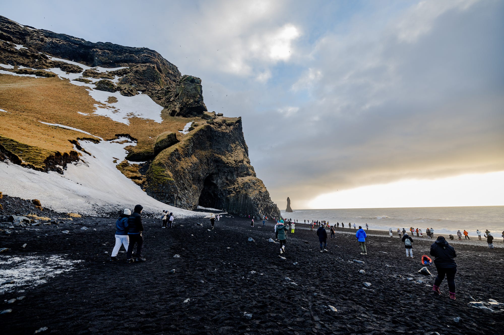 Touristen besuchen Reynisfjara in Island am 24. Januar 2023.