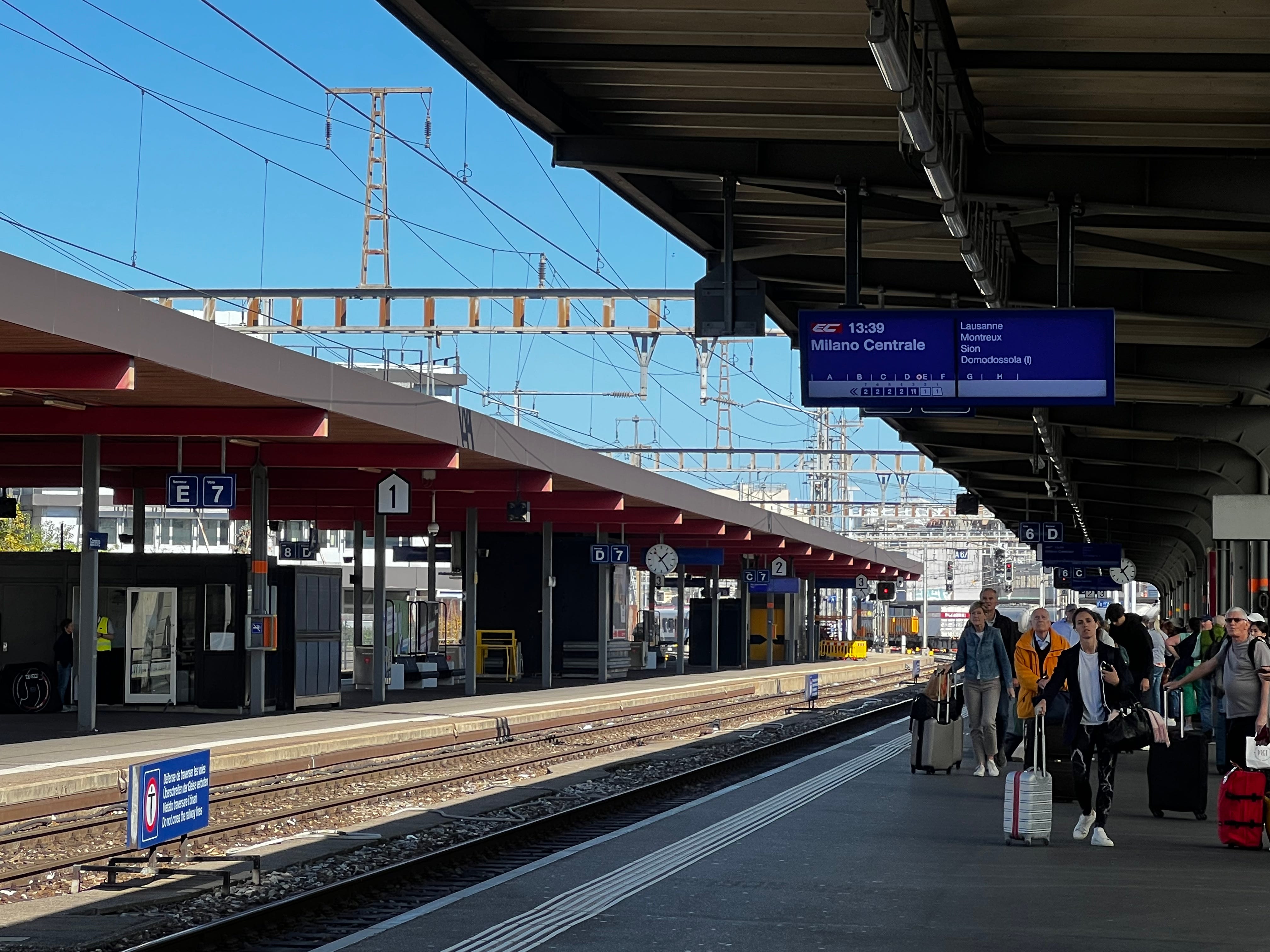 Menschen, die mit Taschen einen Bahnsteig am Genfer Bahnhof hinunterlaufen