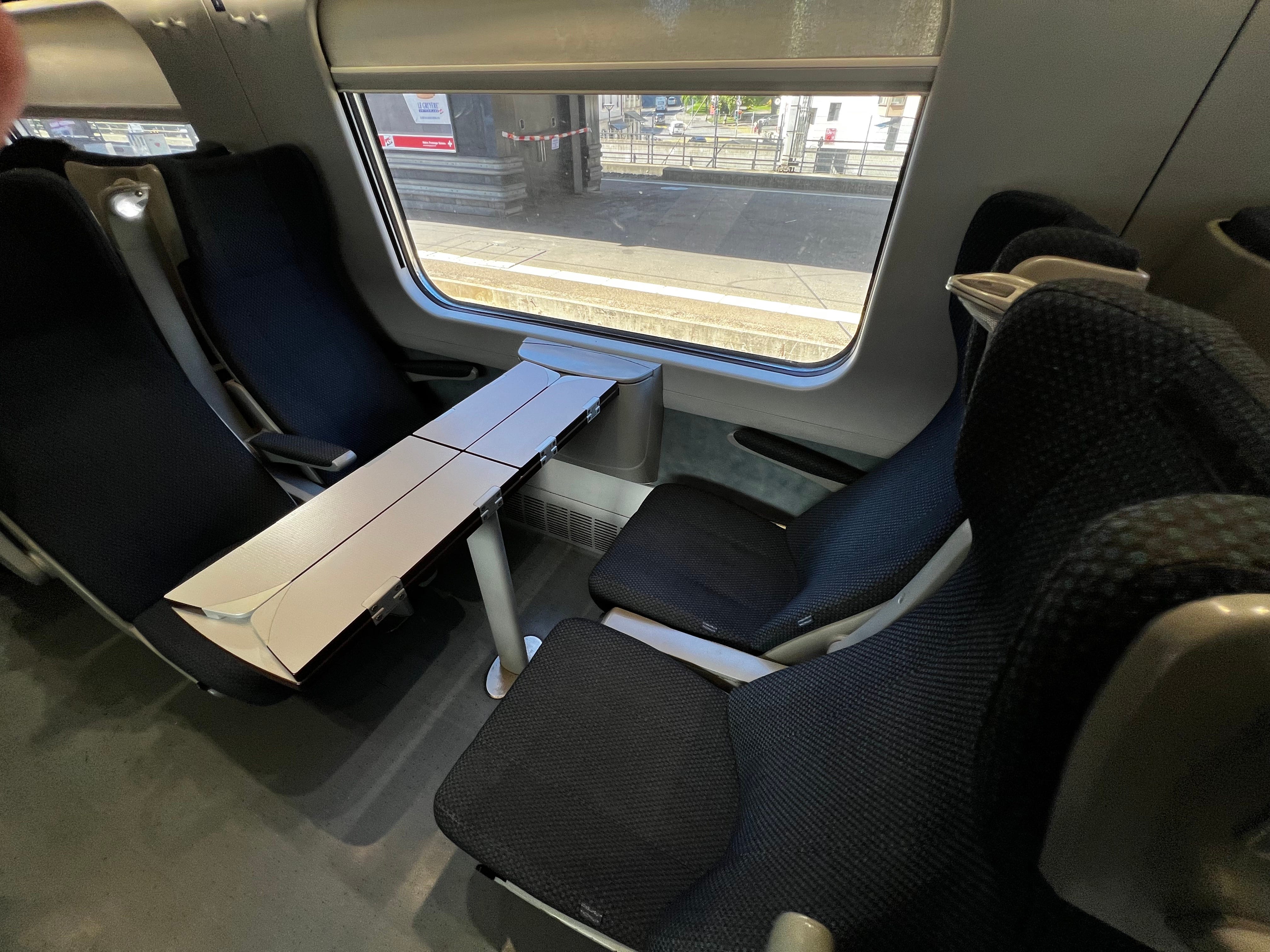 vier Sitze um einen dünnen Tisch in einem europäischen Eisenbahnwaggon