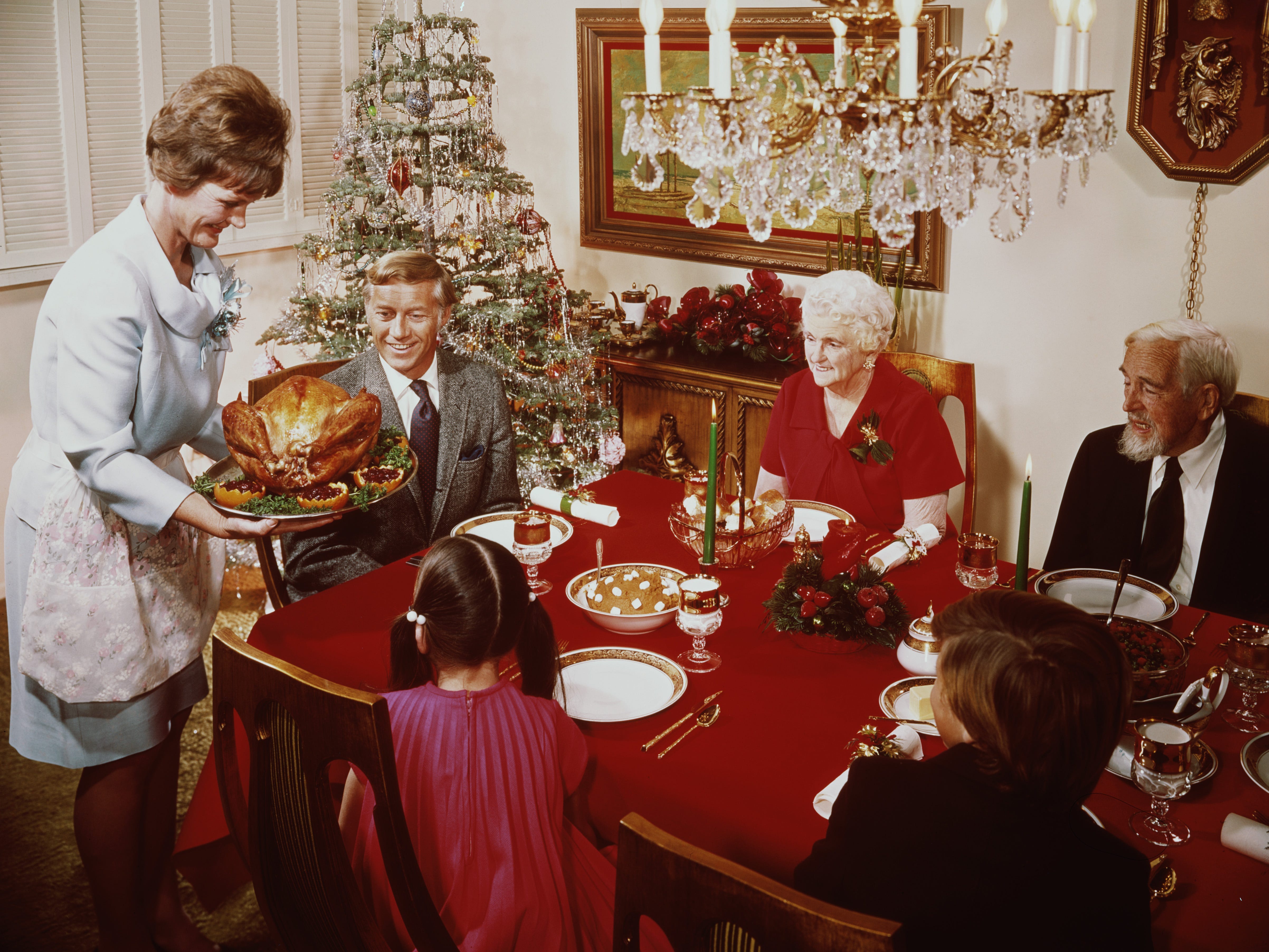 Eine Mutter bringt einen großen Truthahn zum Weihnachtsessen auf den Tisch, etwa 1965.