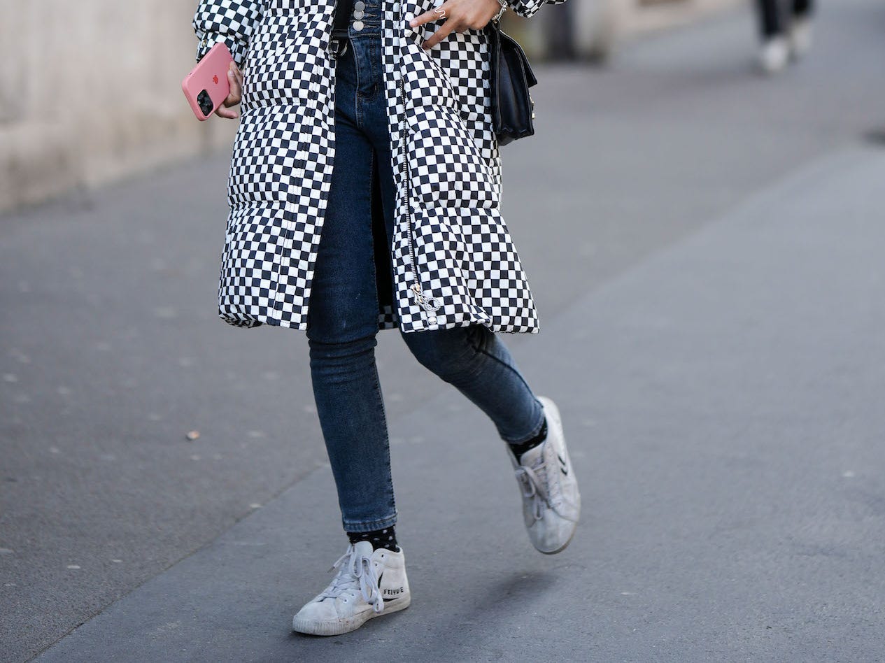 Eine Frau trägt am 1. März 2023 in Paris, Frankreich, Röhrenjeans und einen Mantel mit Schachbrettmuster.