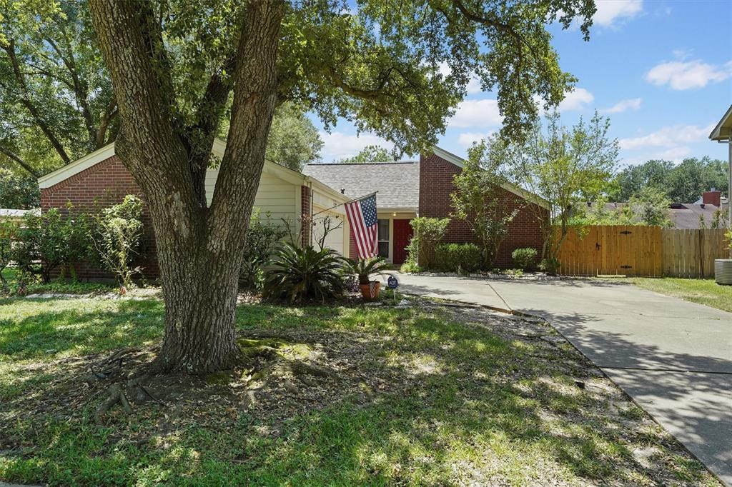 Das Haus der Willicks in Houston, das sie 2023 verkauften. Das Foto zeigt ein Backsteinhaus im Ranch-Stil mit einer Auffahrt und einer amerikanischen Flagge über der Eingangstür.