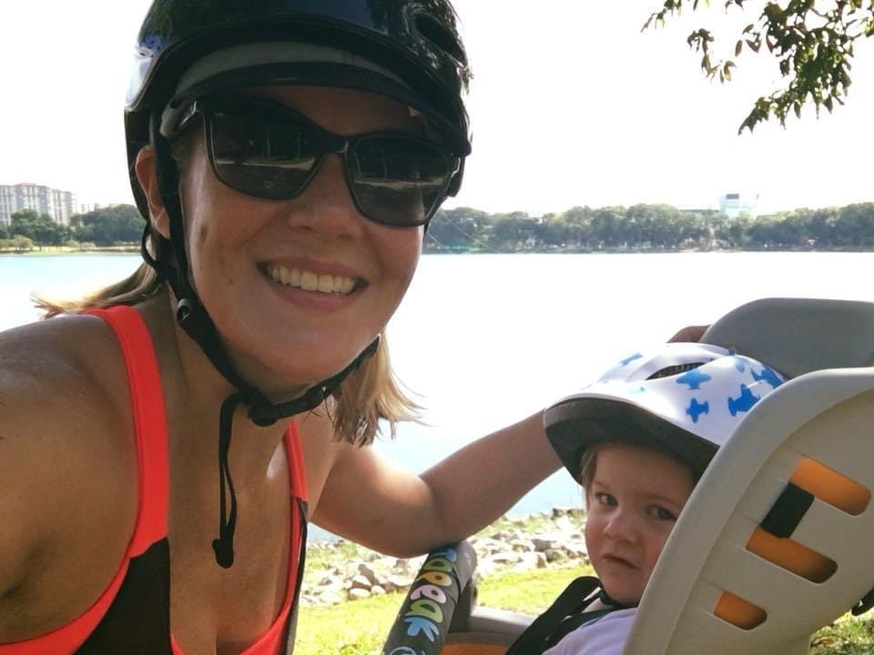 Frau und kleiner Junge im Kindersitz auf einem Fahrrad.