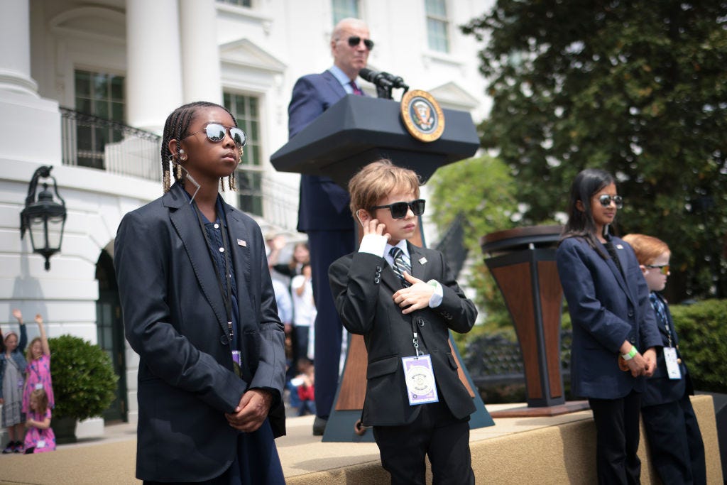 Biden spricht, während als Geheimdienstagenten verkleidete Kinder die Bühne am „Take Your Child To Work Day“ „bewachen“.
