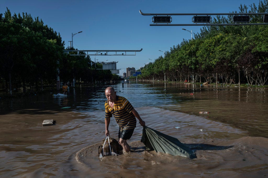 Ein Mann zieht am 5. August 2023 in Zhuozhou, Provinz Hebei südlich von Peking, China, eine Tasche voller aus einem Gebäude geborgener Güter, während er durch das zurückgehende Hochwasser watet.