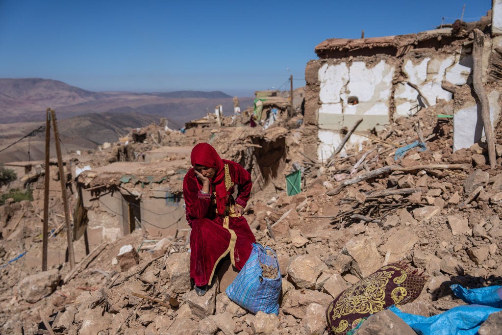 Eine Frau sitzt inmitten der Trümmer ihres Dorfes, das durch ein Erdbeben in Marokko fast vollständig zerstört wurde