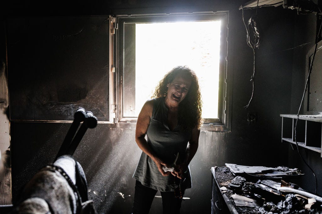 Die Bewohnerin des Kibbuz Nir Oz, Hadas Kalderon, deren Kinder als Geiseln genommen und ihre Mutter und Nichte getötet wurden, bricht in Tränen aus, als sie durch das ausgebrannte Haus ihrer verstorbenen Mutter schaut