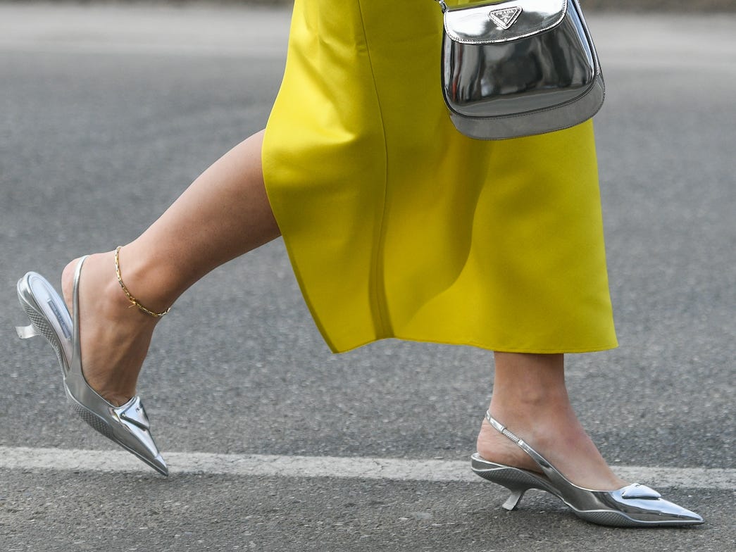 Metallische Schuhe gepaart mit einer metallischen Handtasche und einem gelben Rock.