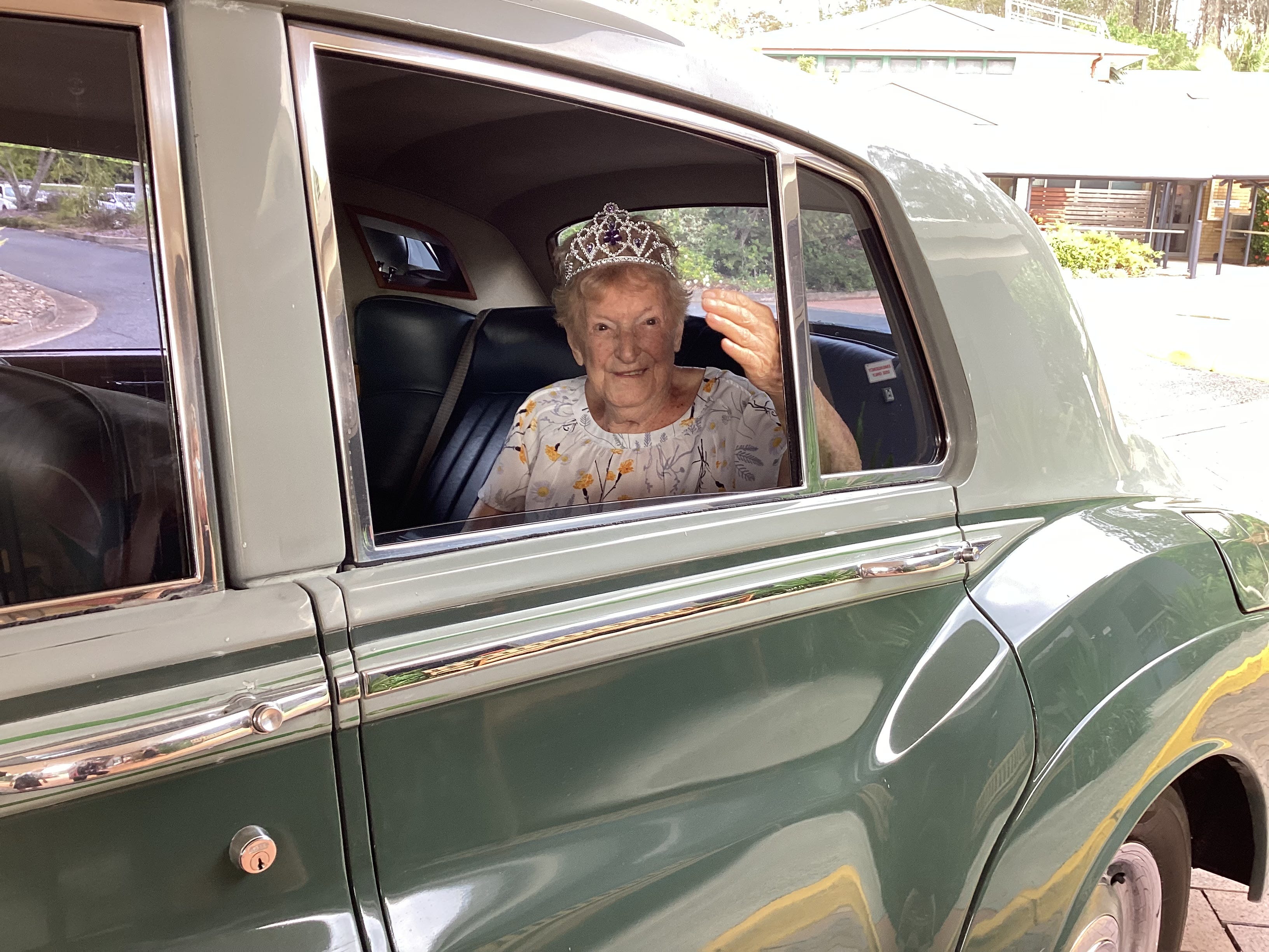 Die Hundertjährige Katie MacRae sitzt an ihrem 106. Geburtstag auf dem Rücksitz eines alten Autos und trägt eine Tiara.