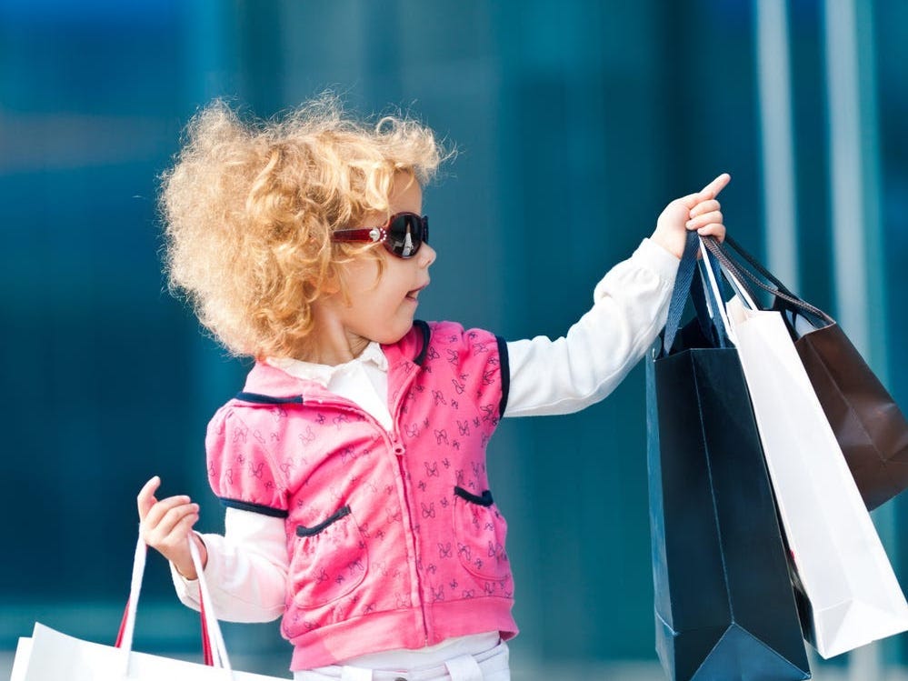 Ein kleines Mädchen mit Sonnenbrille und Einkaufstüten in der Hand