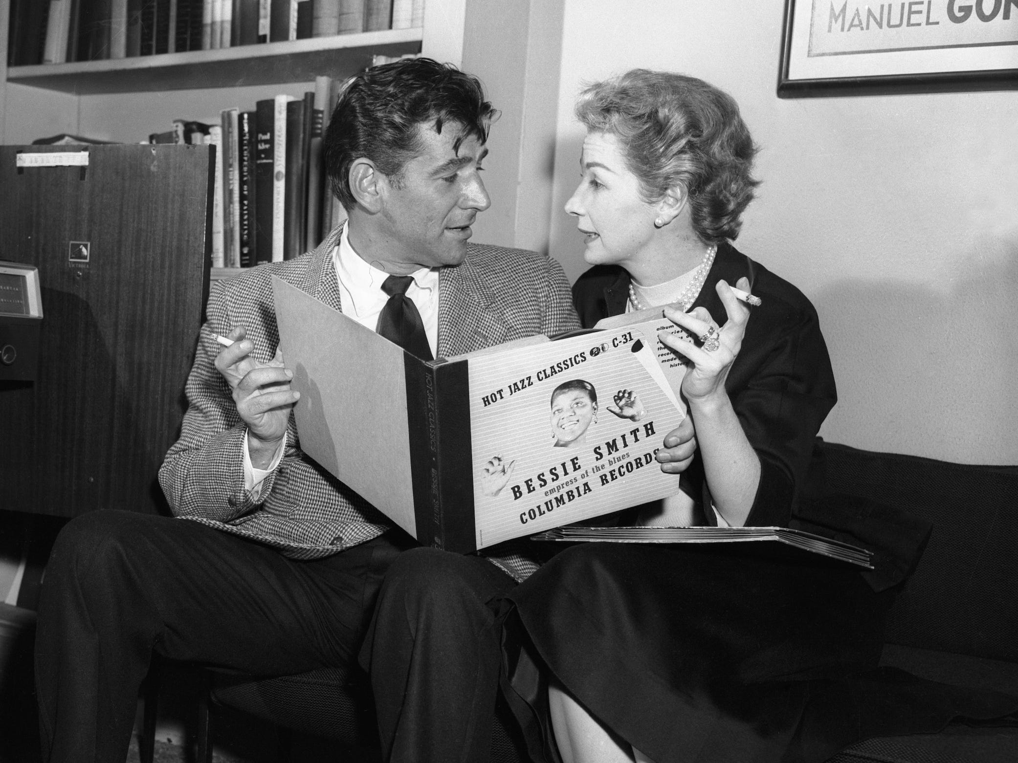 Auf diesem Schwarzweißfoto von 1956 sitzen Leonard Bernstein und Felicia Montealegre auf einer Couch, beide in der Hand Zigaretten und ein Schallplattenalbum.