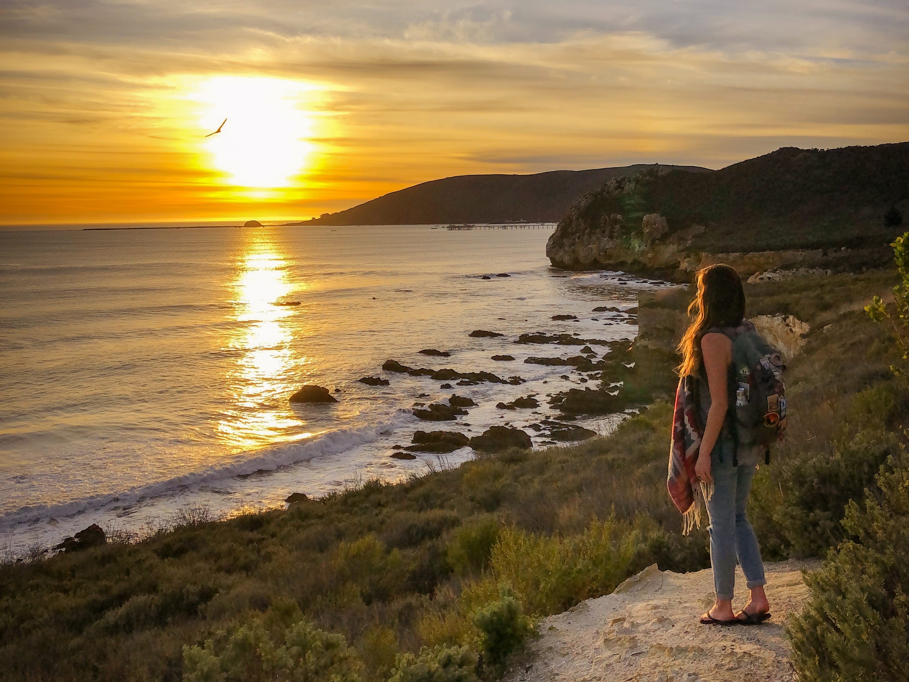 Emily blickt auf den Sonnenuntergang an einem kalifornischen Strand.