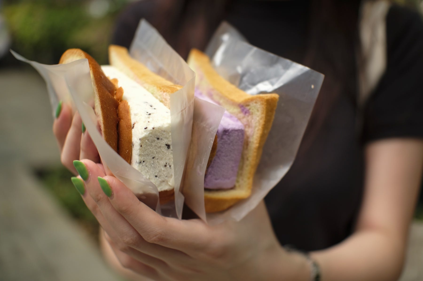 Eine Nahaufnahme der Hände einer Frau, die zwei traditionelle Eiscremesandwiches hält.