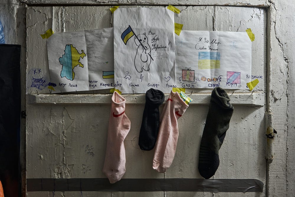 Rosa und schwarze „Geschenksocken“ mit kleinen Geschenken und Karten von Kindern, genagelt unter Kinderzeichnungen am Eingang der Militärresidenz am 24. Dezember 2023 in der Region Bachmut, Ukraine.