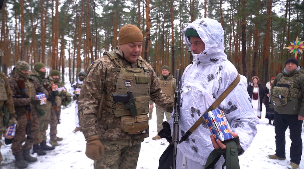 Generalleutnant Serhii Naiev (links) steht am 25. Dezember 2023 mit einem ukrainischen Soldaten und anderen im Rücken in einem verschneiten Waldgebiet im Norden der Ukraine.