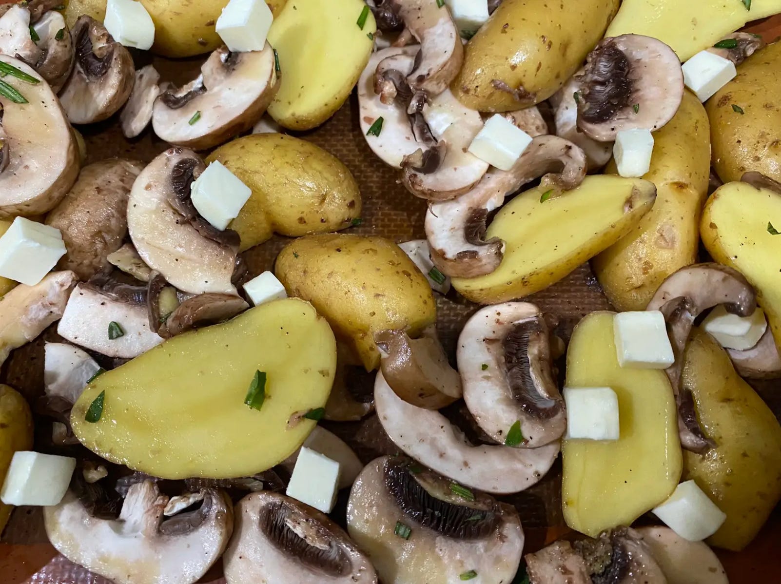 Pilze, Kartoffeln, Butter und Gewürze auf einem Blech verteilen