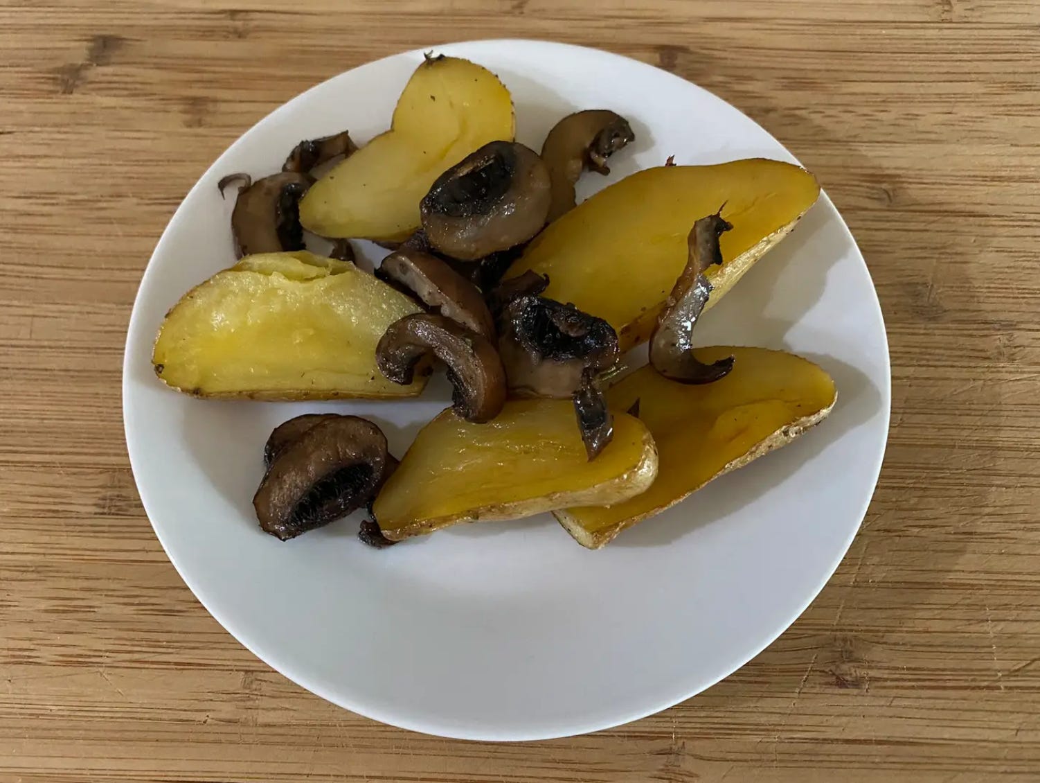 Geröstete Pilze und Kartoffeln auf einem weißen Teller
