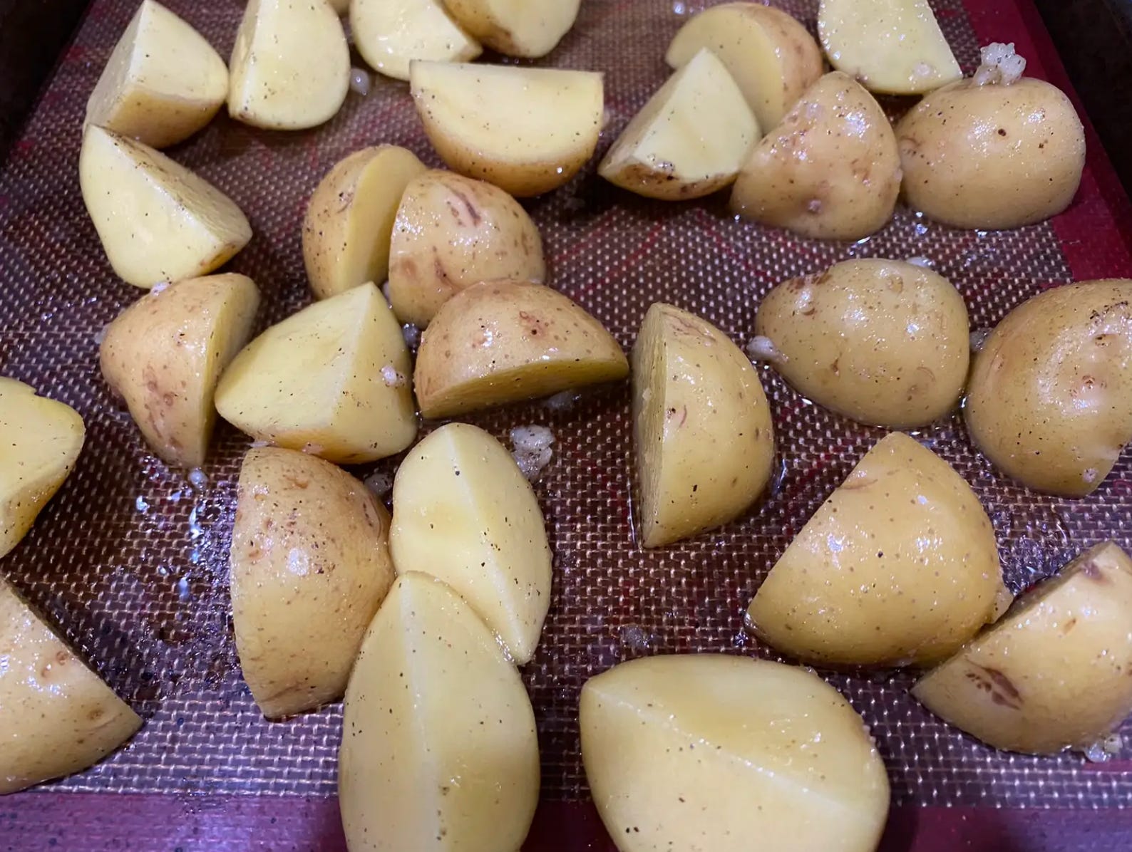 Stücke gewürzter Kartoffeln auf einem Blech verteilen