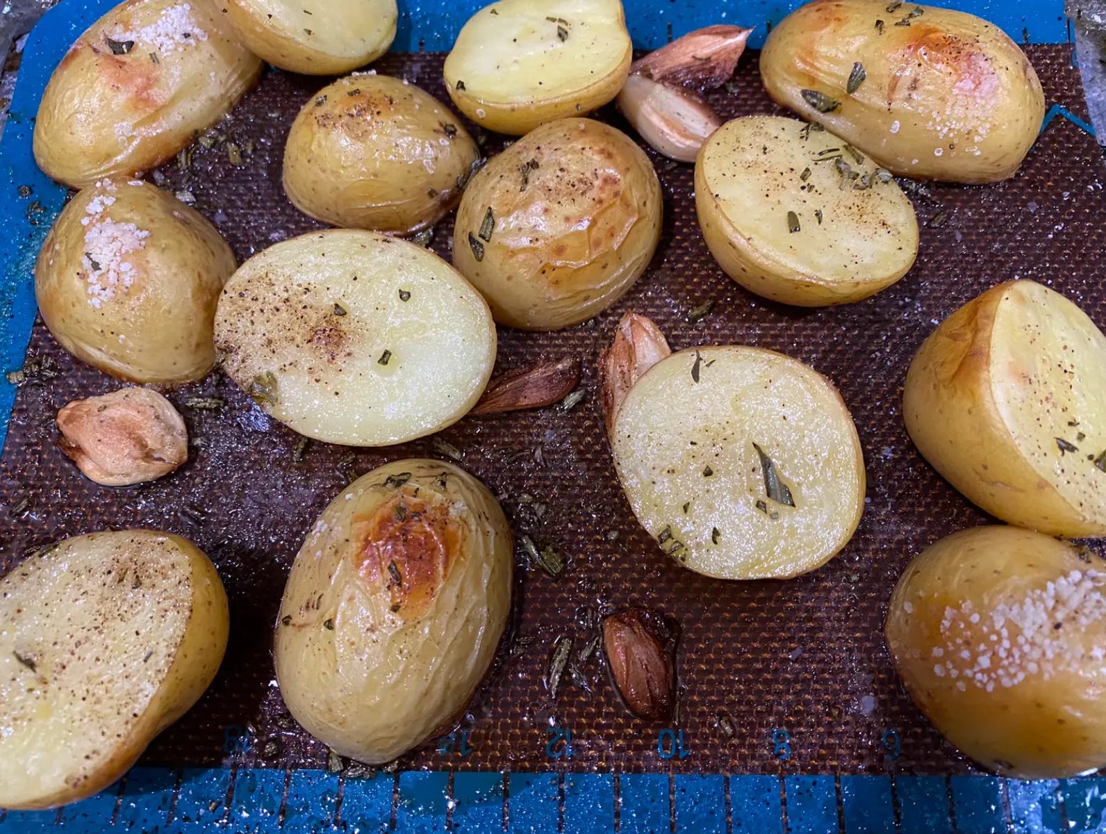 knusprig geröstete Kartoffeln auf einer Blechpfanne mit Knoblauch und Rosmarin