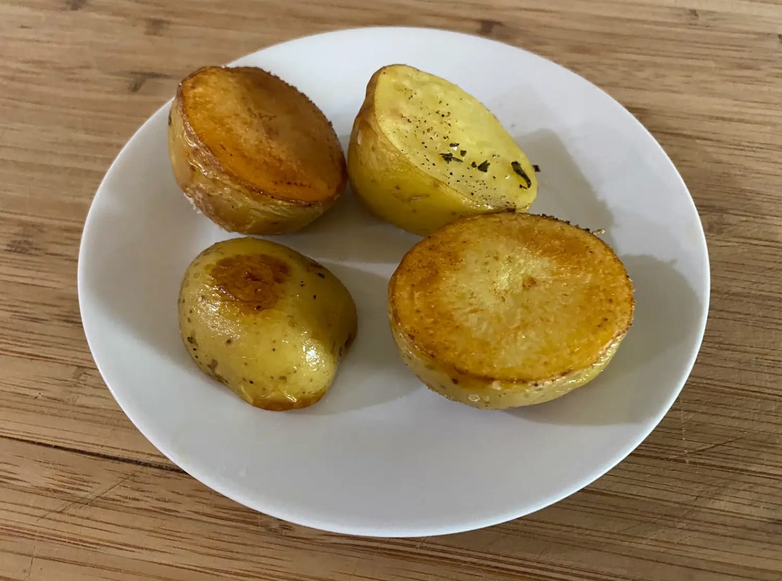 vier goldbraun geröstete Kartoffelhälften auf einem weißen Teller