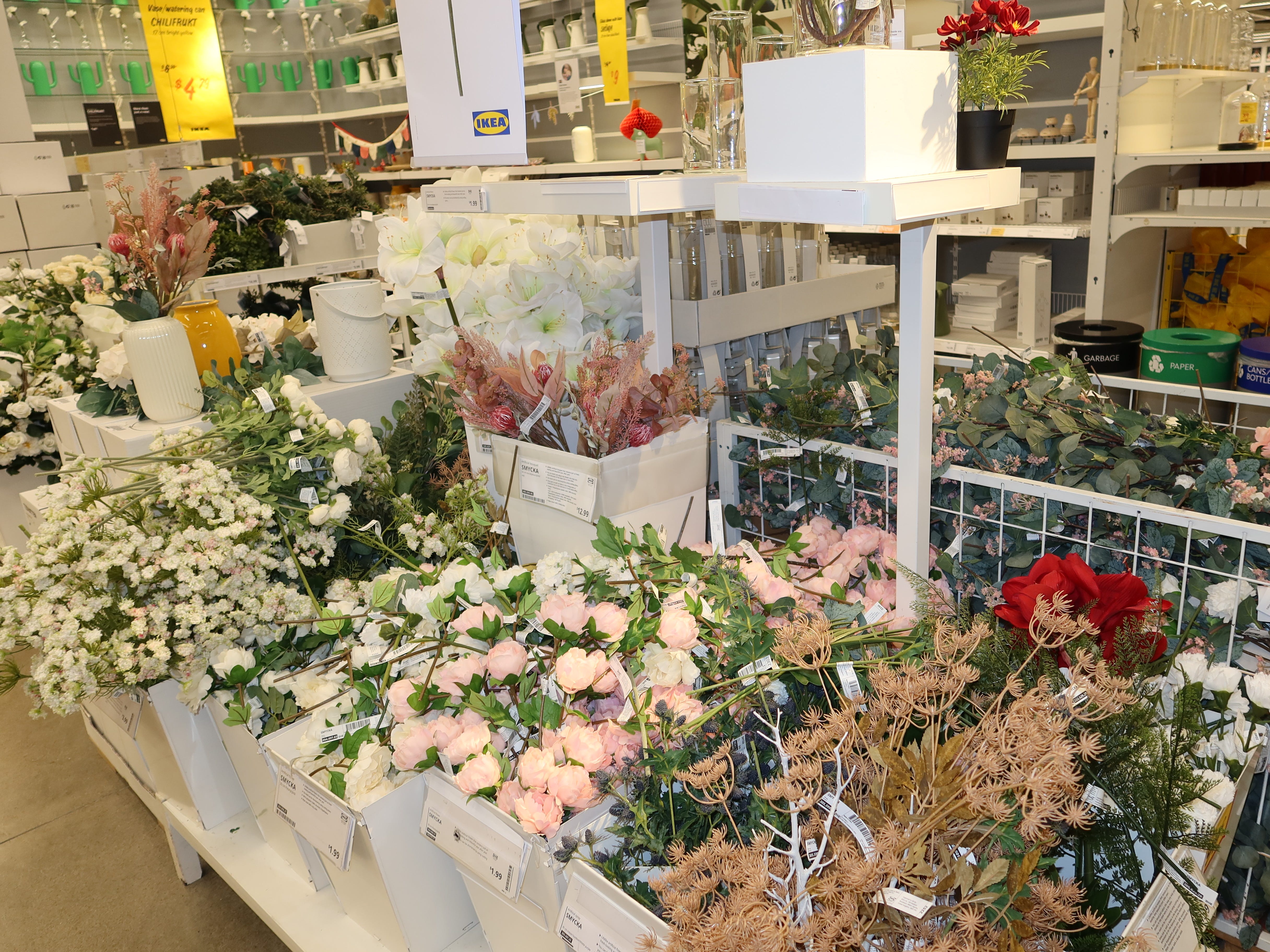 Körbe mit künstlichen rosa, weißen und braunen Blumen bei Ikea