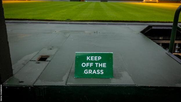 Centre Court im Hintergrund eines Schildes mit der Aufschrift „Keep Off the Grass“.