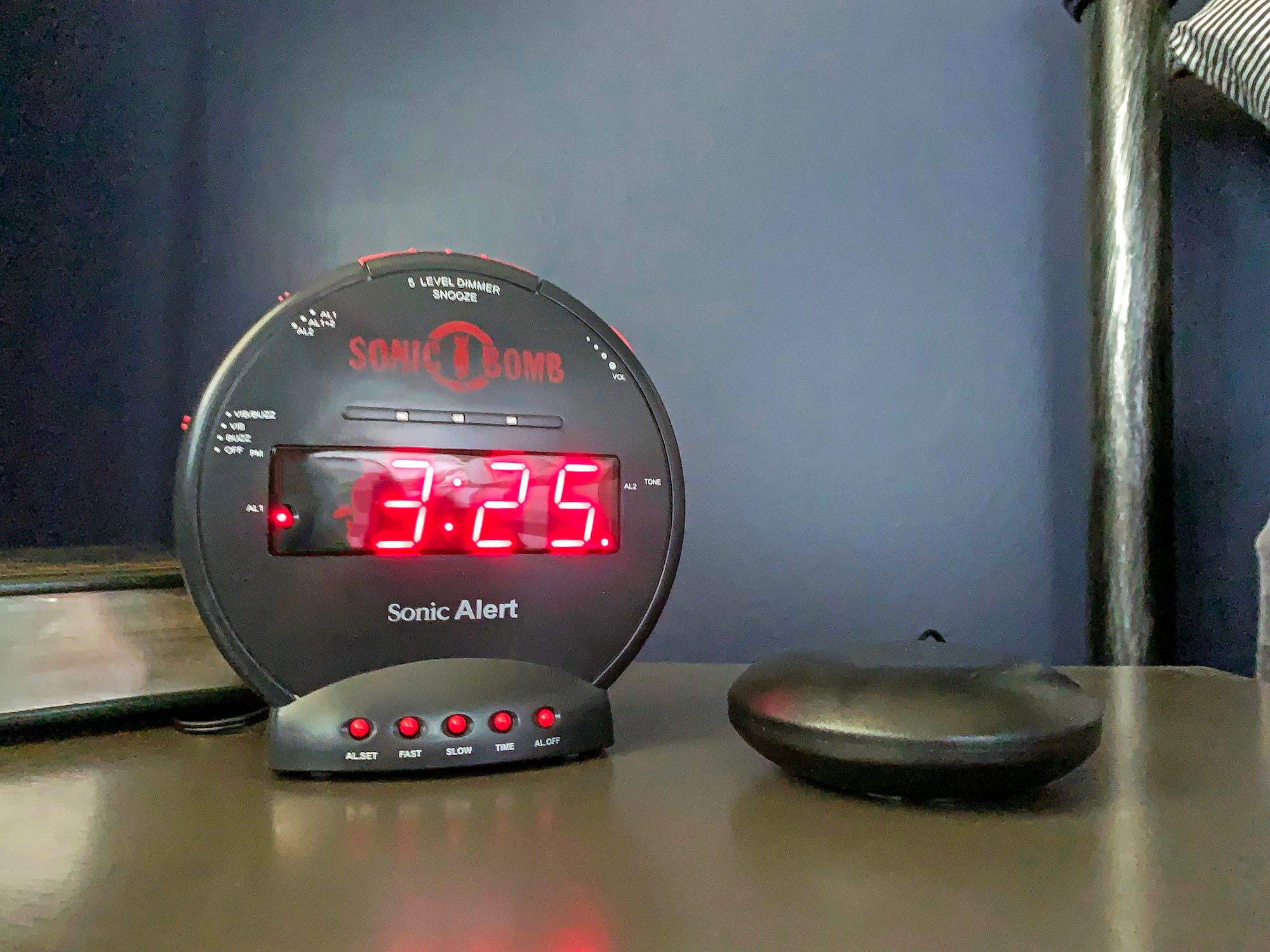 Der Sonic Alert Sonic Bomb Dual Extra-Loud Wecker mit Bed Shaker steht auf einem Nachttisch und zeigt 3:25 an.