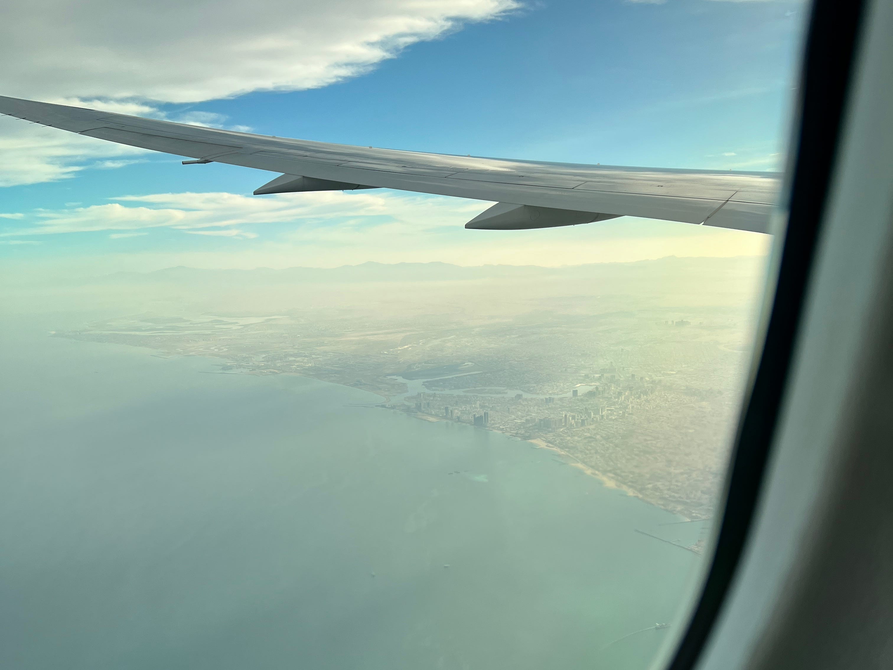 Ein Blick auf die Küste Dubais aus dem Fenster eines Boeing 787 Dreamliners mit sichtbarem Flügel.