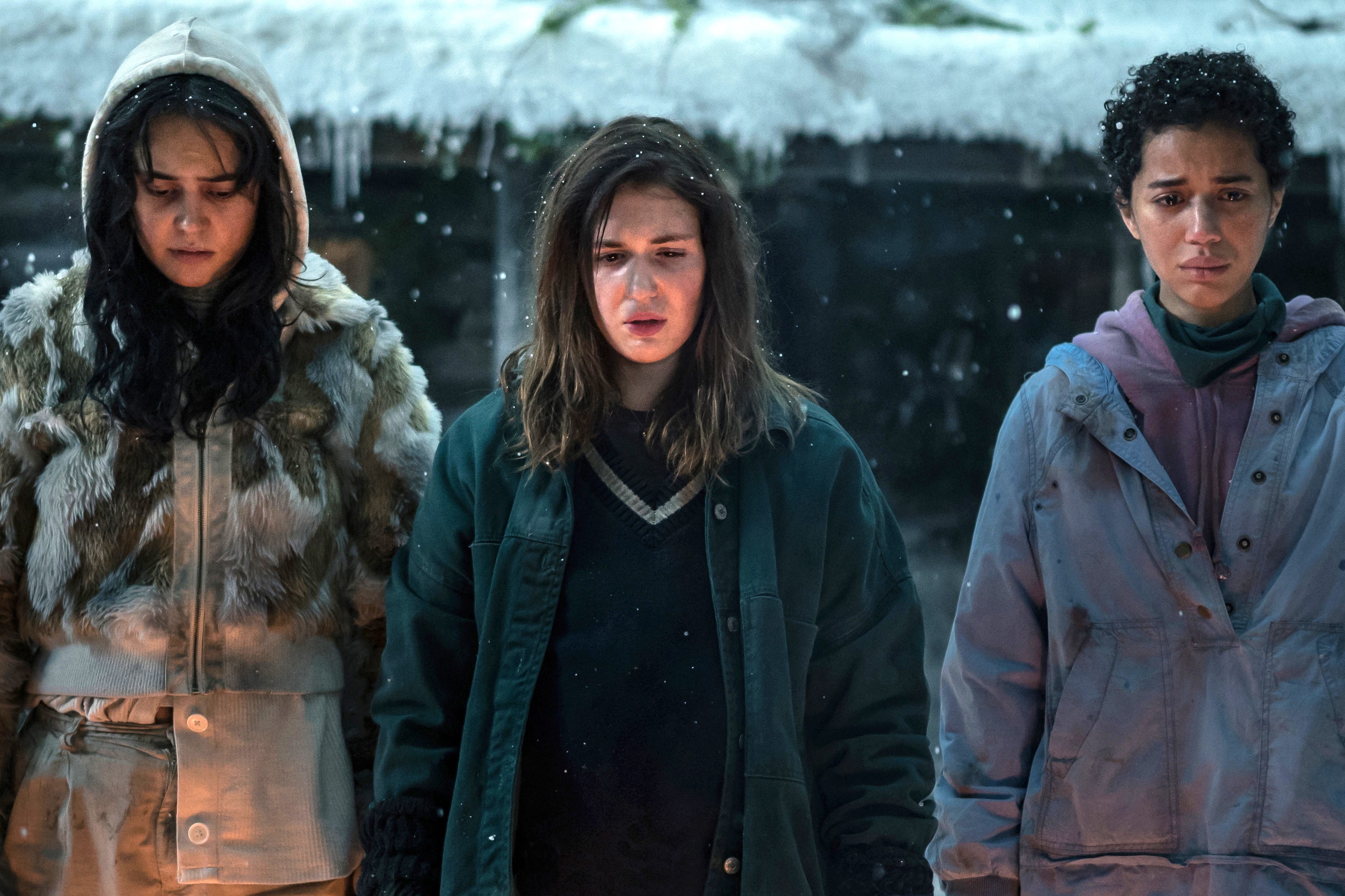 Die Teenager Lottie, Shauna und Taissa stehen eingepackt draußen im Schnee und beobachten ein Feuer in diesem Foto aus Staffel zwei, Folge zwei von „Yellowjackets“.