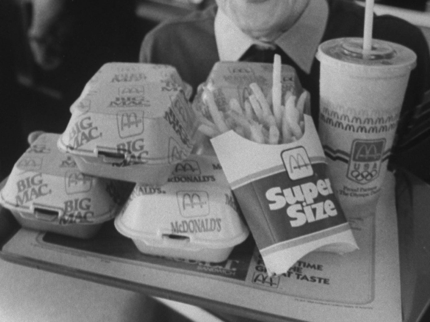 Eine Frau hält ein Tablett mit McDonald's-Essen, etwa 1988