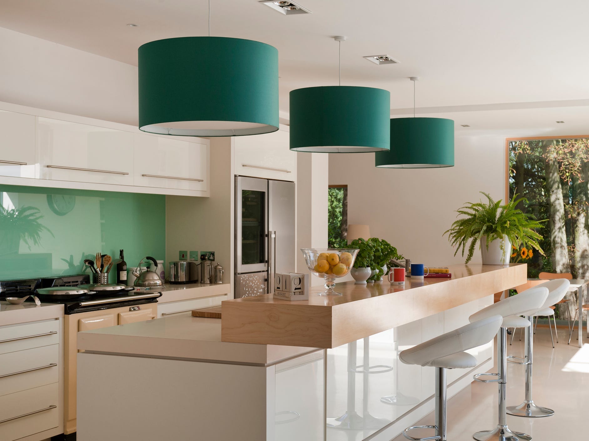 Moderne Küche mit grüner Rückwand und Lampenschirmen