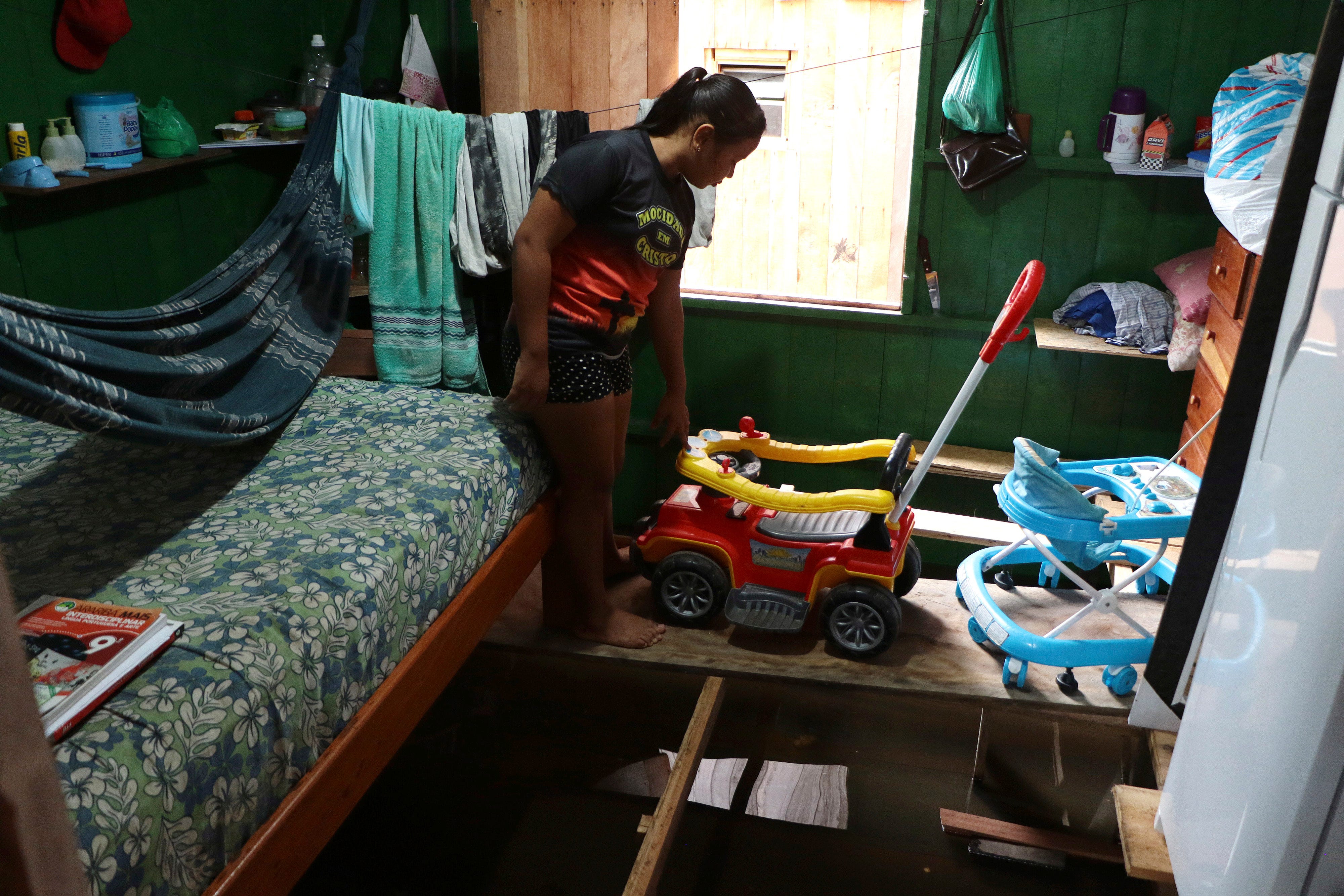Valeria Ribeiro de Souza geht auf einem Holzbrett, das Möbel in ihrem Haus in Anama im brasilianischen Bundesstaat Amazonas über dem Wasser hält