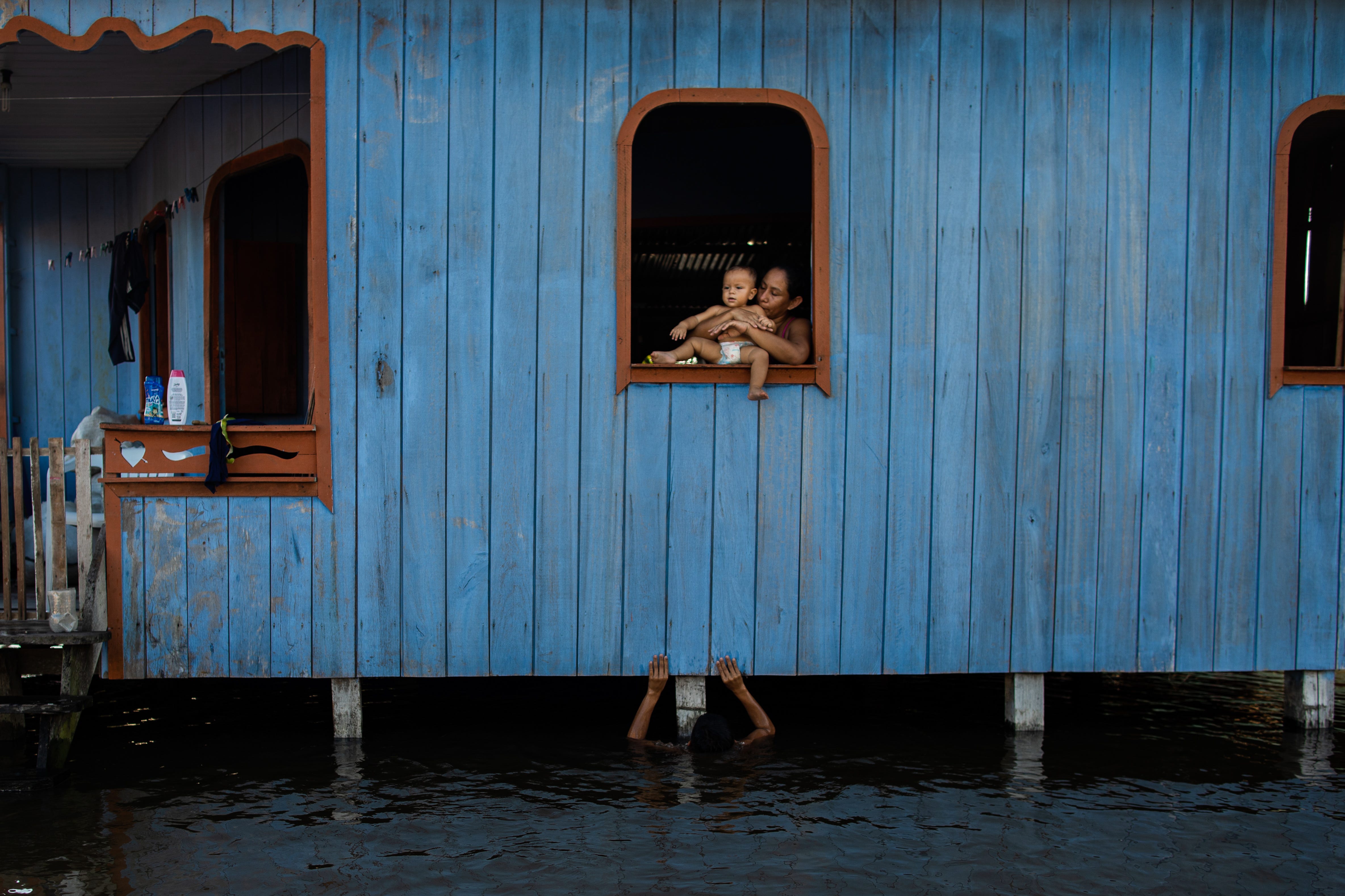 Eine Frau hält ihren Neffen in einem Haus, das von Wasser umgeben ist