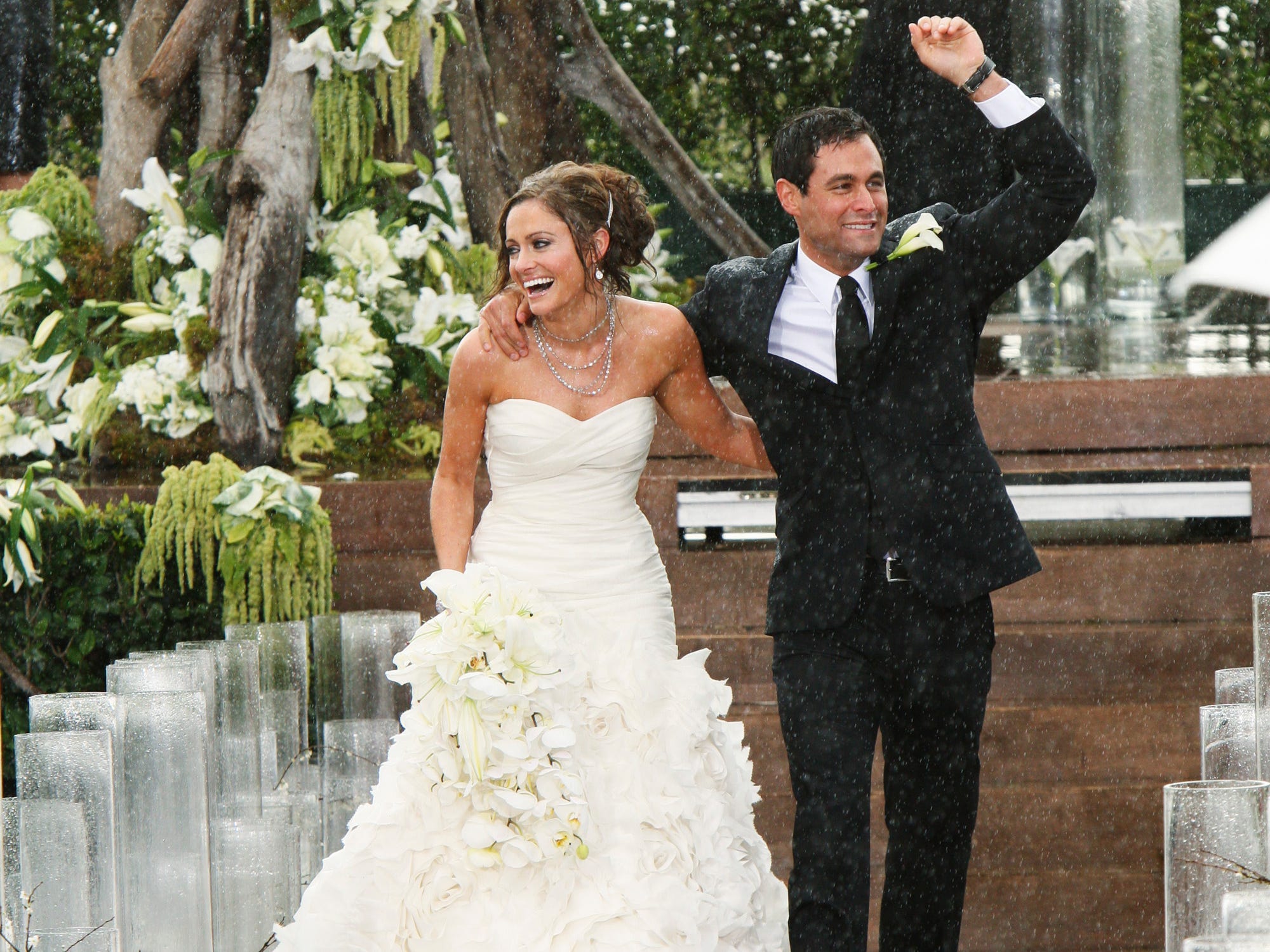 Molly Malaney geht nach ihrer Hochzeit im Jahr 2010 in einem weißen trägerlosen Kleid und einem Blumenstrauß mit Ehemann Jason Mesnick den Altar entlang.