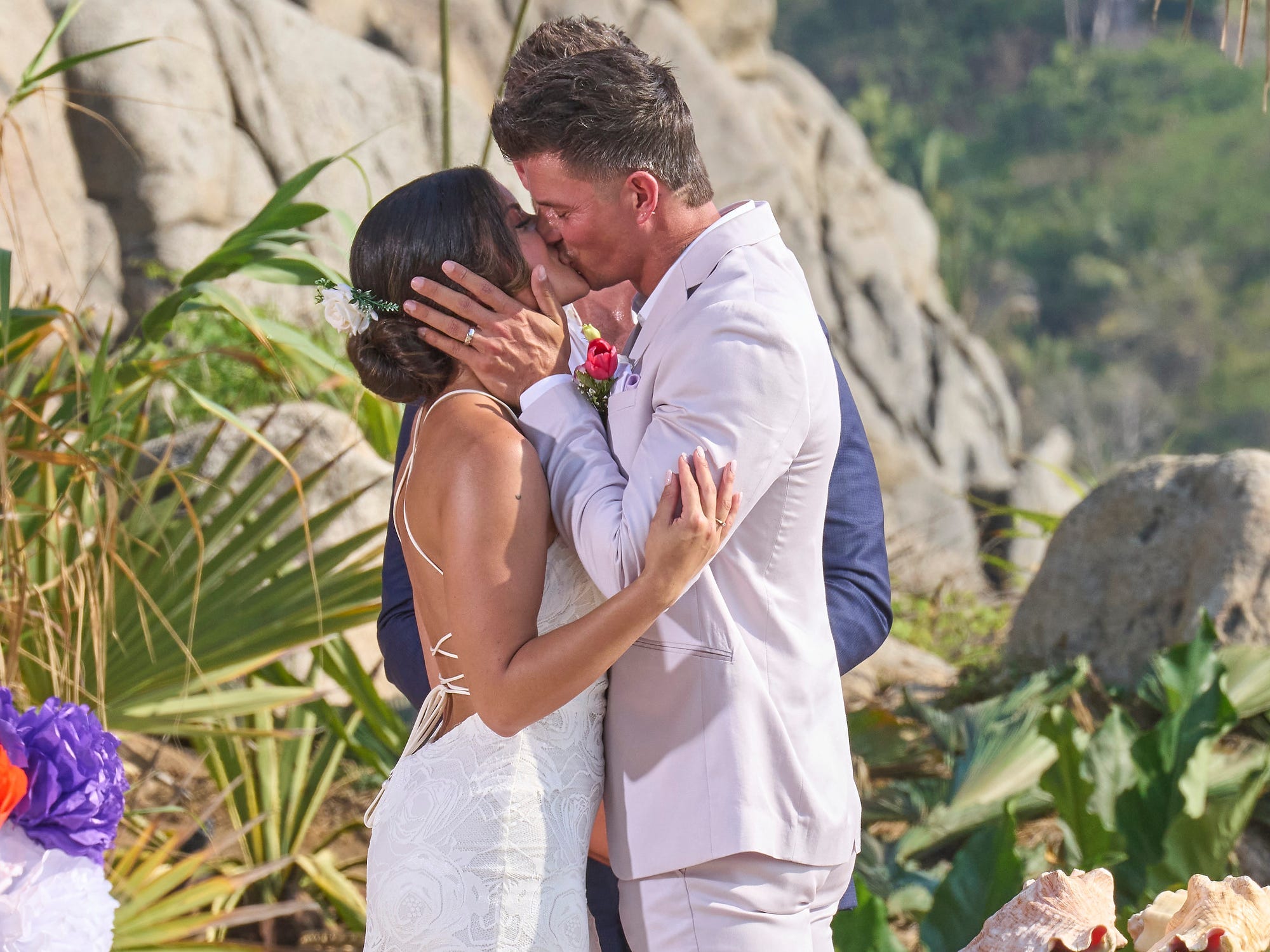 Mari Pepin, in einem weißen rückenfreien Hochzeitskleid, küsst Kenny Braasch, in einem weißen Anzug, während ihrer Hochzeitszeremonie in Staffel 9 von „Bachelor in Paradise“.