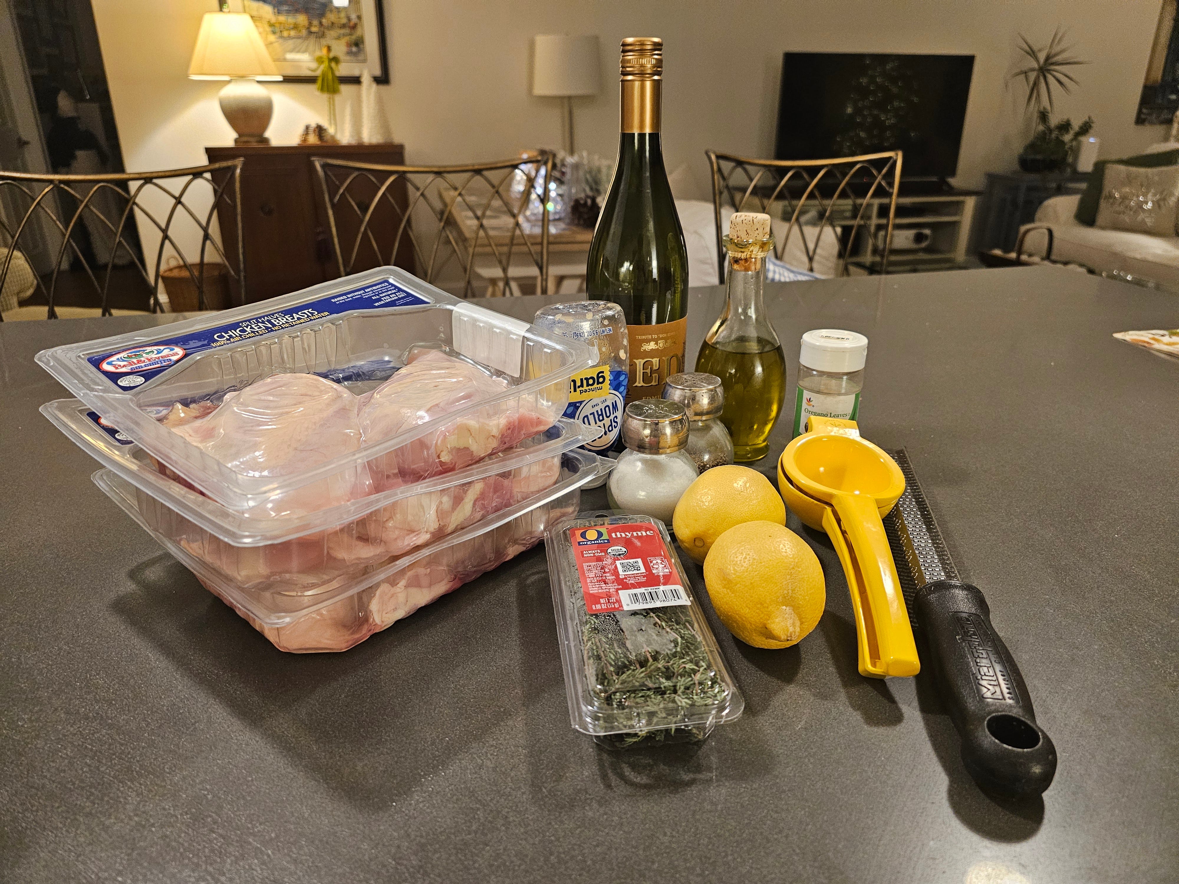 Pakete mit Hähnchenbrust, Thymian, zwei Zitronen, Saftpresse, Olivenöl auf der Theke