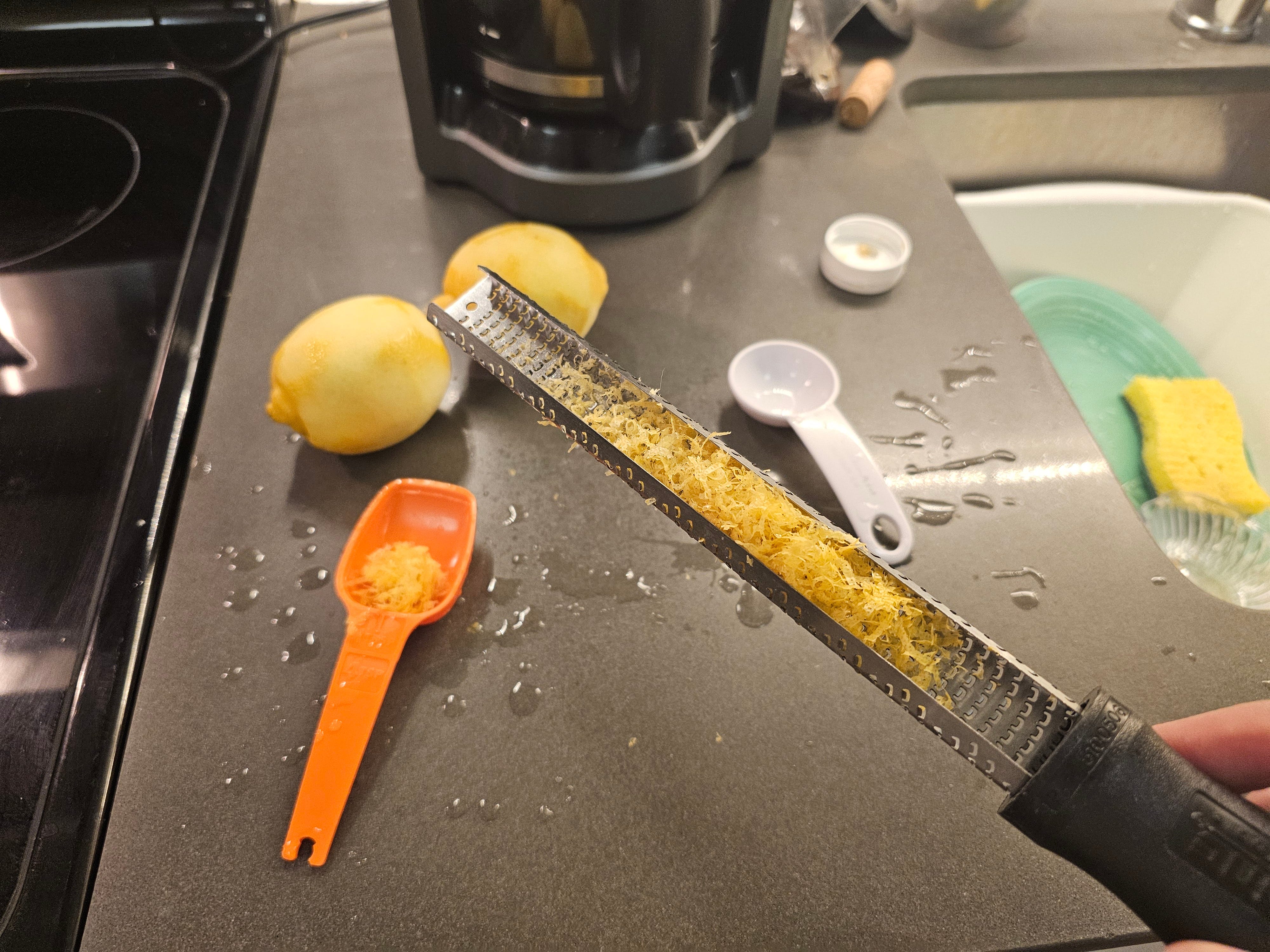 Microplane-Zester gefüllt mit Zitronenschale über zwei gehobelten Zitronen