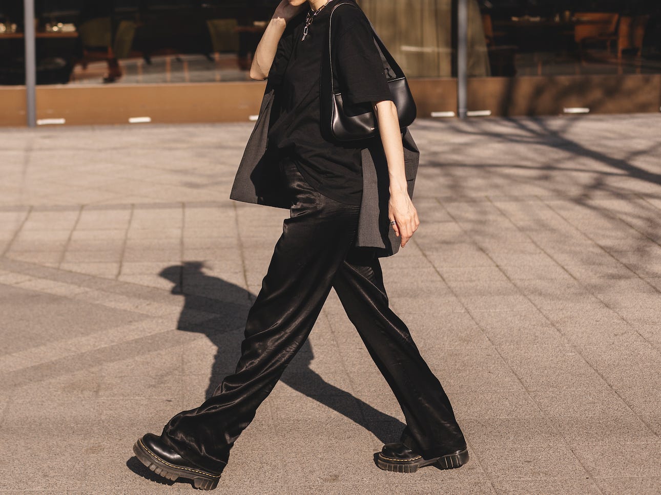 Frau geht die Straße entlang und trägt ein komplett schwarzes Outfit mit schwarzen Accessoires