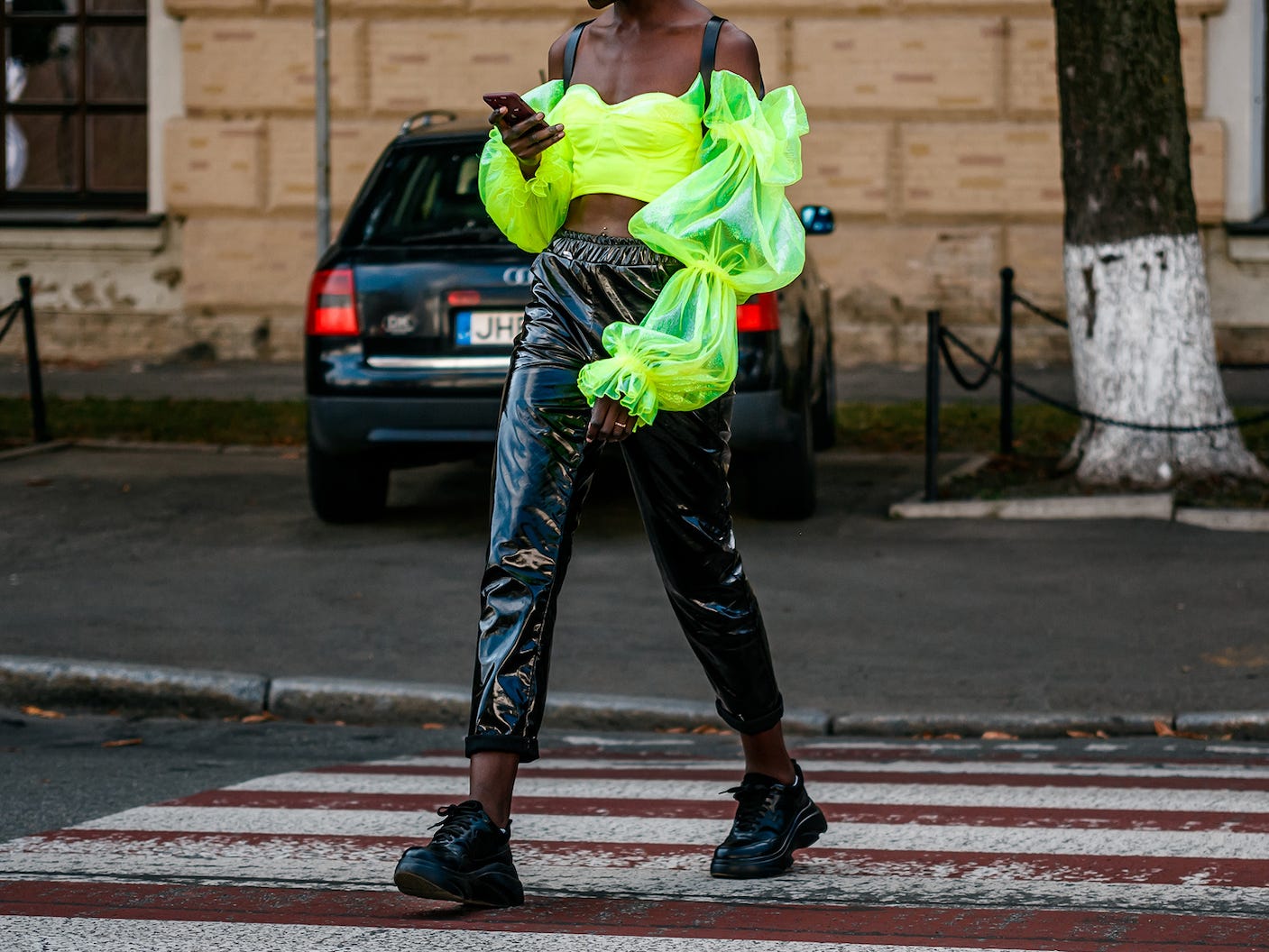 Person, die eine Straße entlang geht und ein neongelbes Hemd und Pflanzenlederhosen trägt