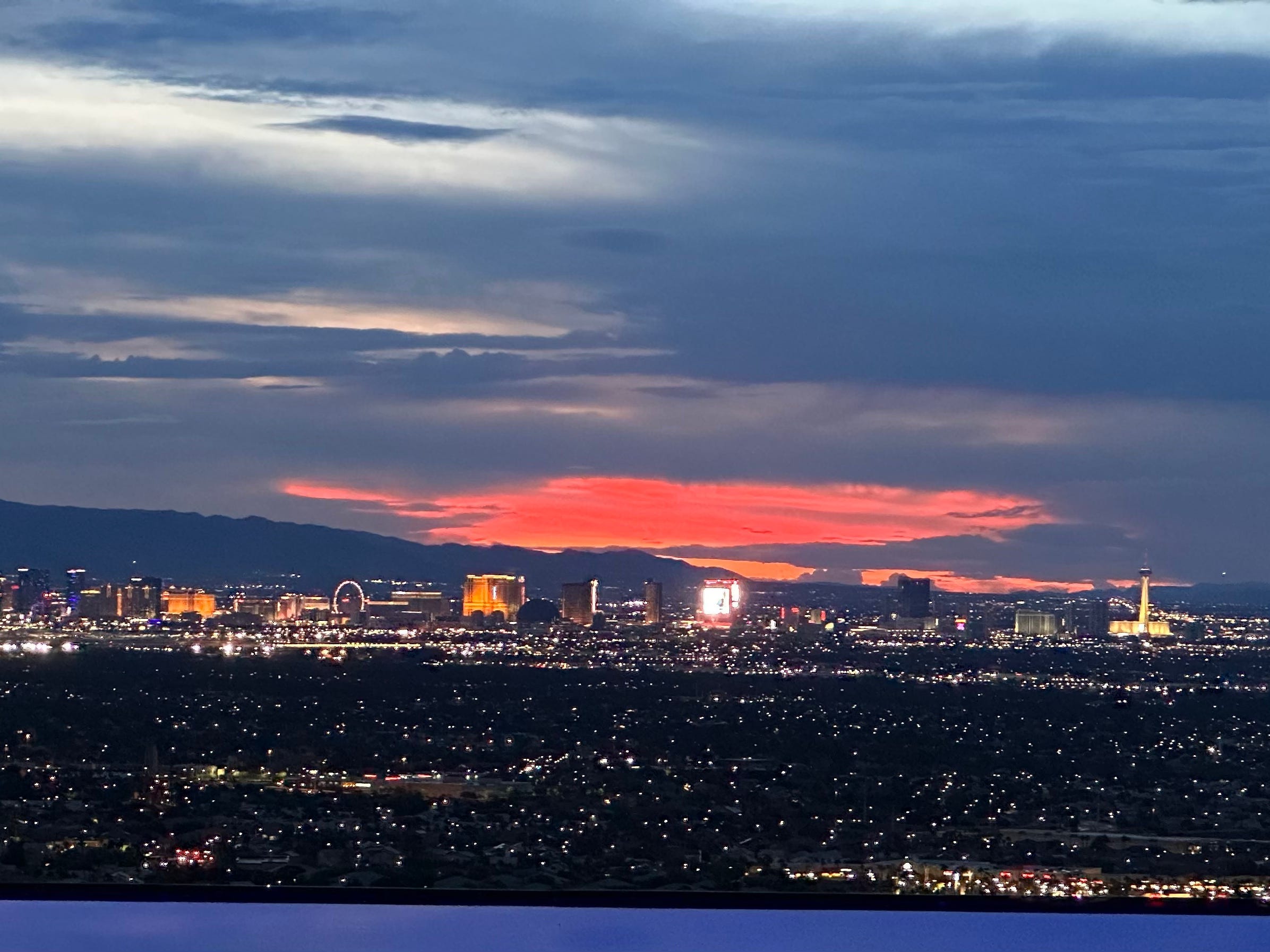Ein Blick auf den Nachthimmel über Las Vegas, wo die untergehende Sonne ein helles rotes Licht gegen den bewölkten Himmel geworfen hat.