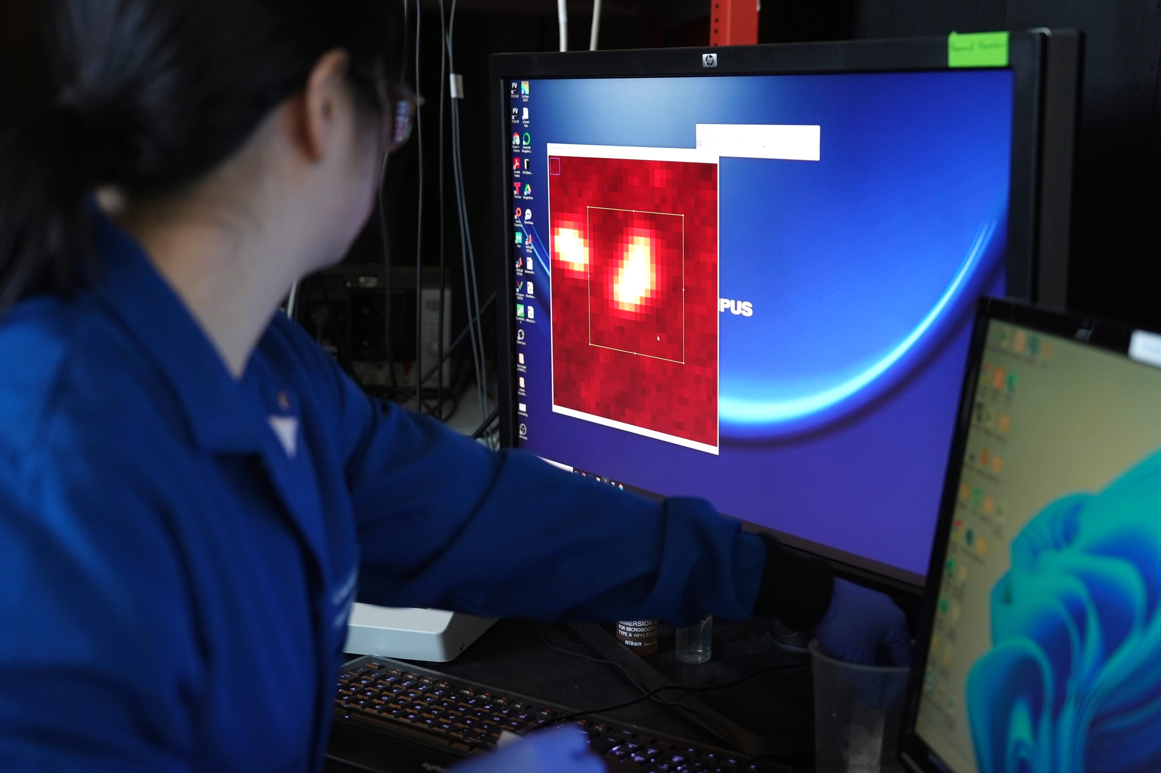 Ein Chemiker zoomt in einen Computerbildschirm und zeigt Mikroplastik als leuchtend rote Punkte.